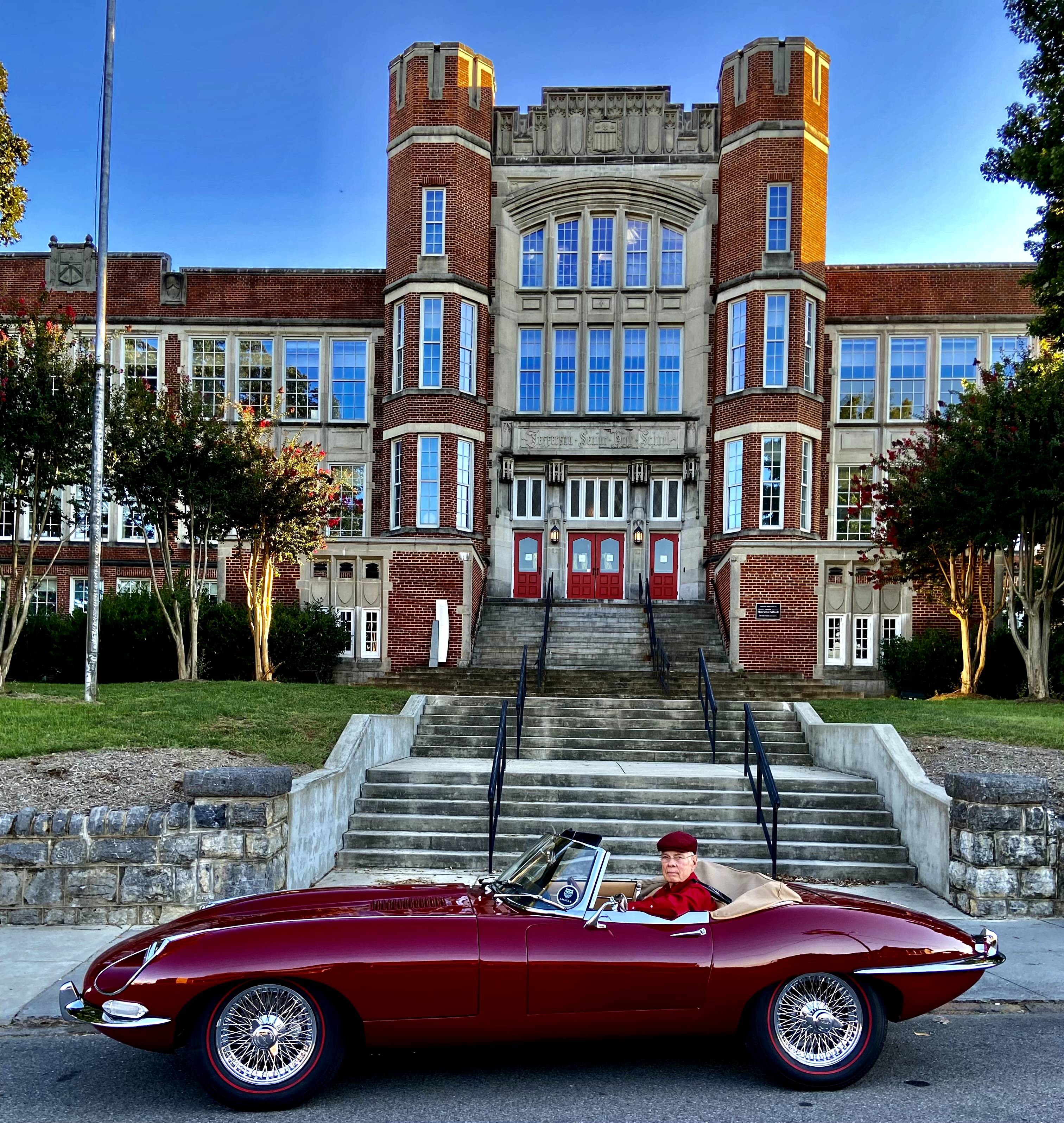 A man in a maroon sports car parked in front of the Jefferson Center in Roanoke.