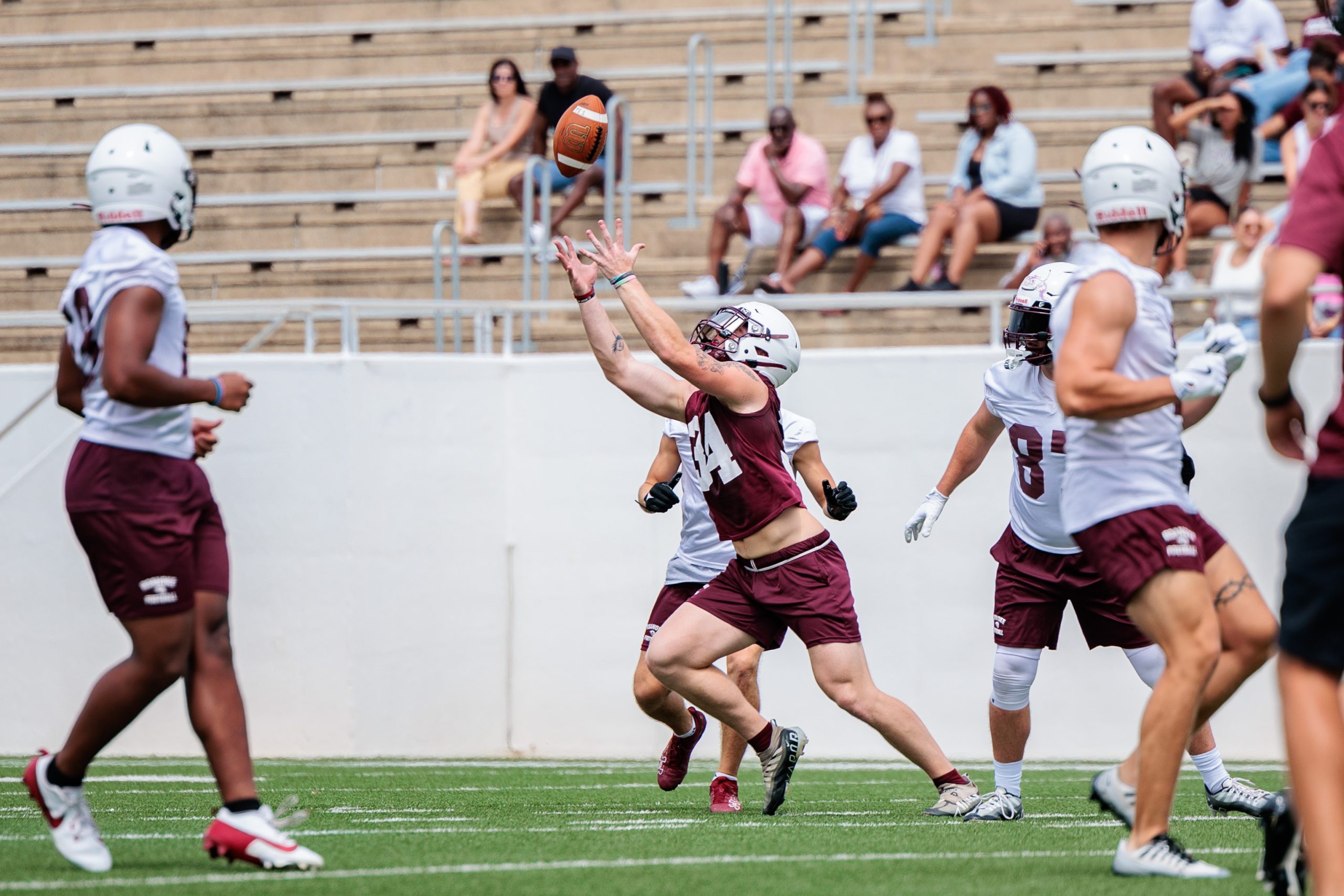 The Roanoke College football team, in maroon and white uniforms, practices on their home field.