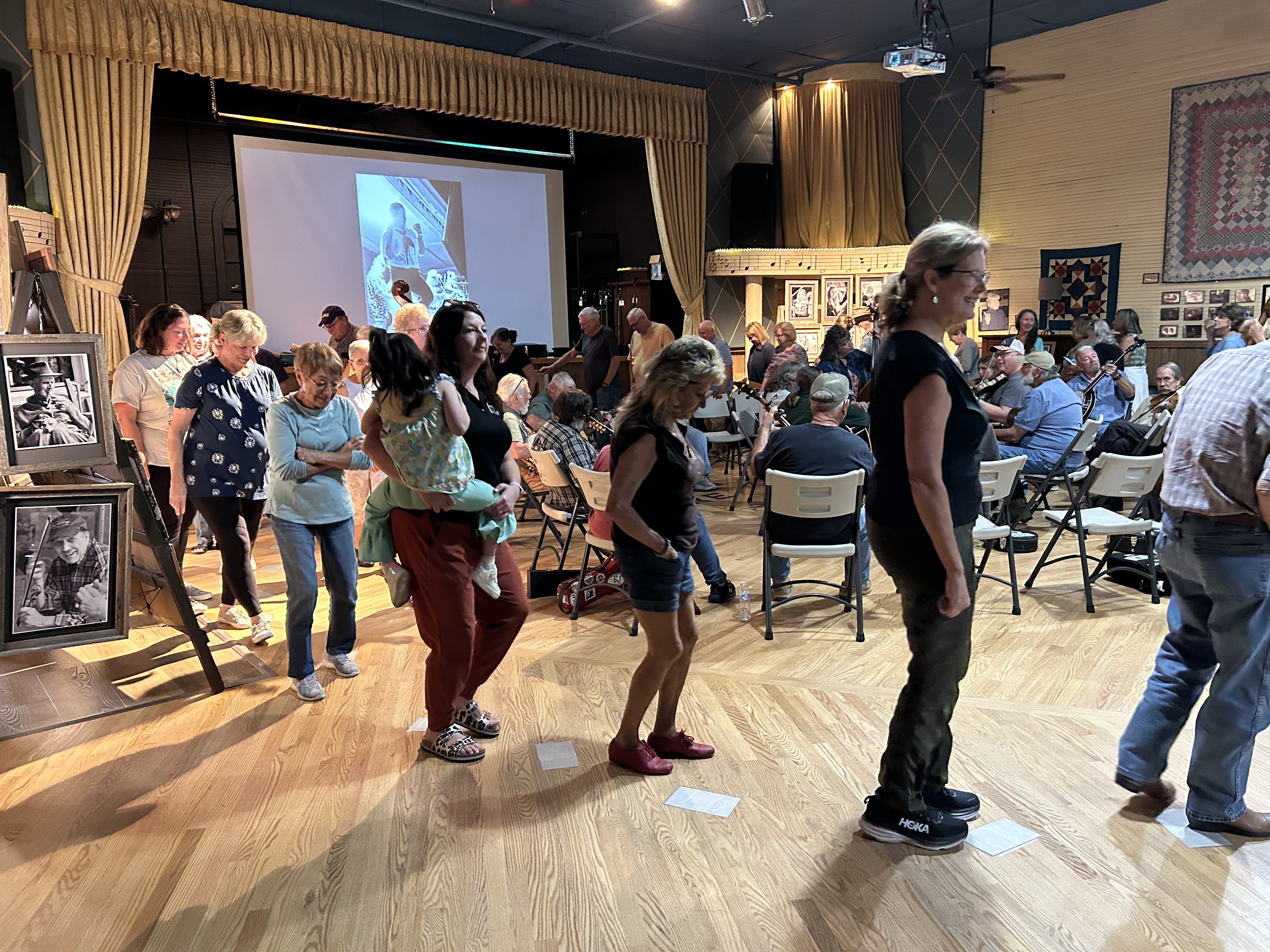 People participate in a cakewalk during an old-time mountain music jam session at the Fries Theatre. When the music stopped, participants stood on a number written on pieces of paper on the floor. The person with the winning number took home a cake. Ruth Babylon photo