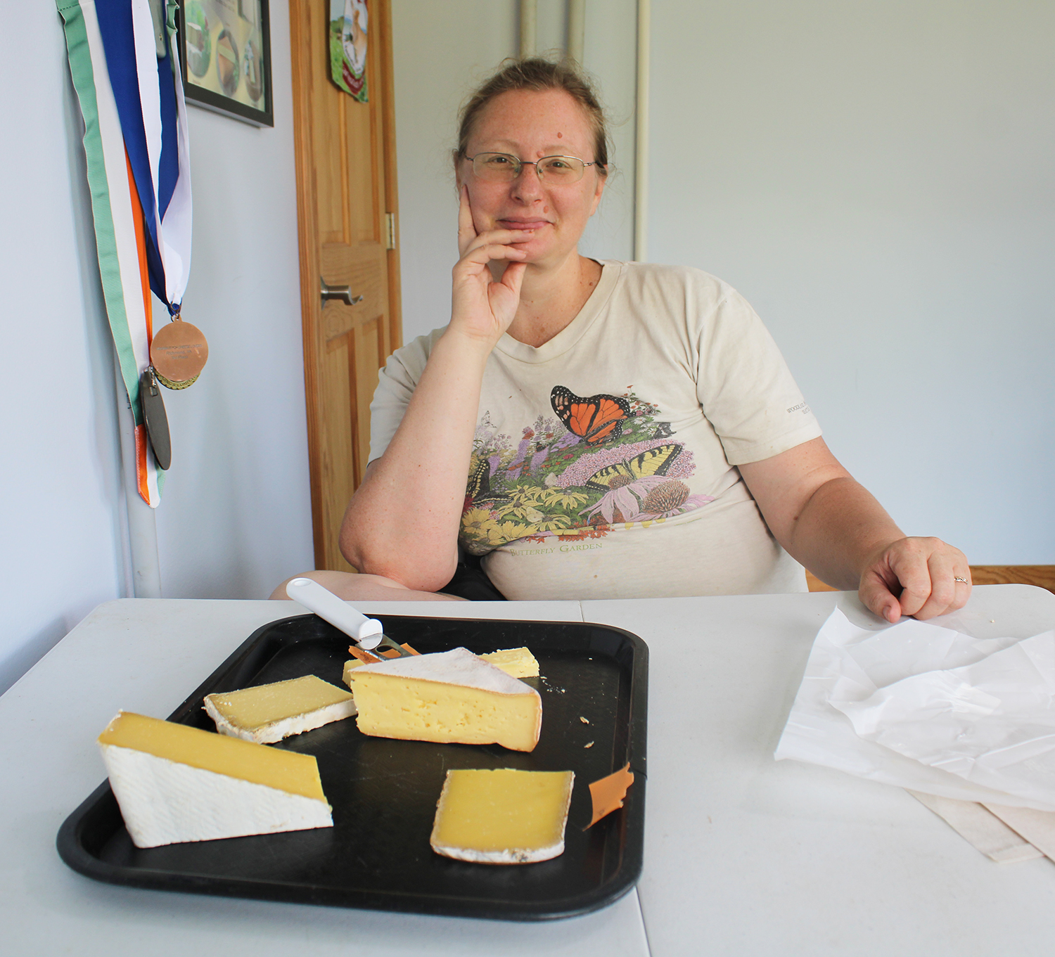 A cheese tasting offered by Kat Feete, daughter of Meadow Creek Dairy’s founder/owner Feete family, next to some of the business’s many, many medals. Photo by Shannon Watkins.