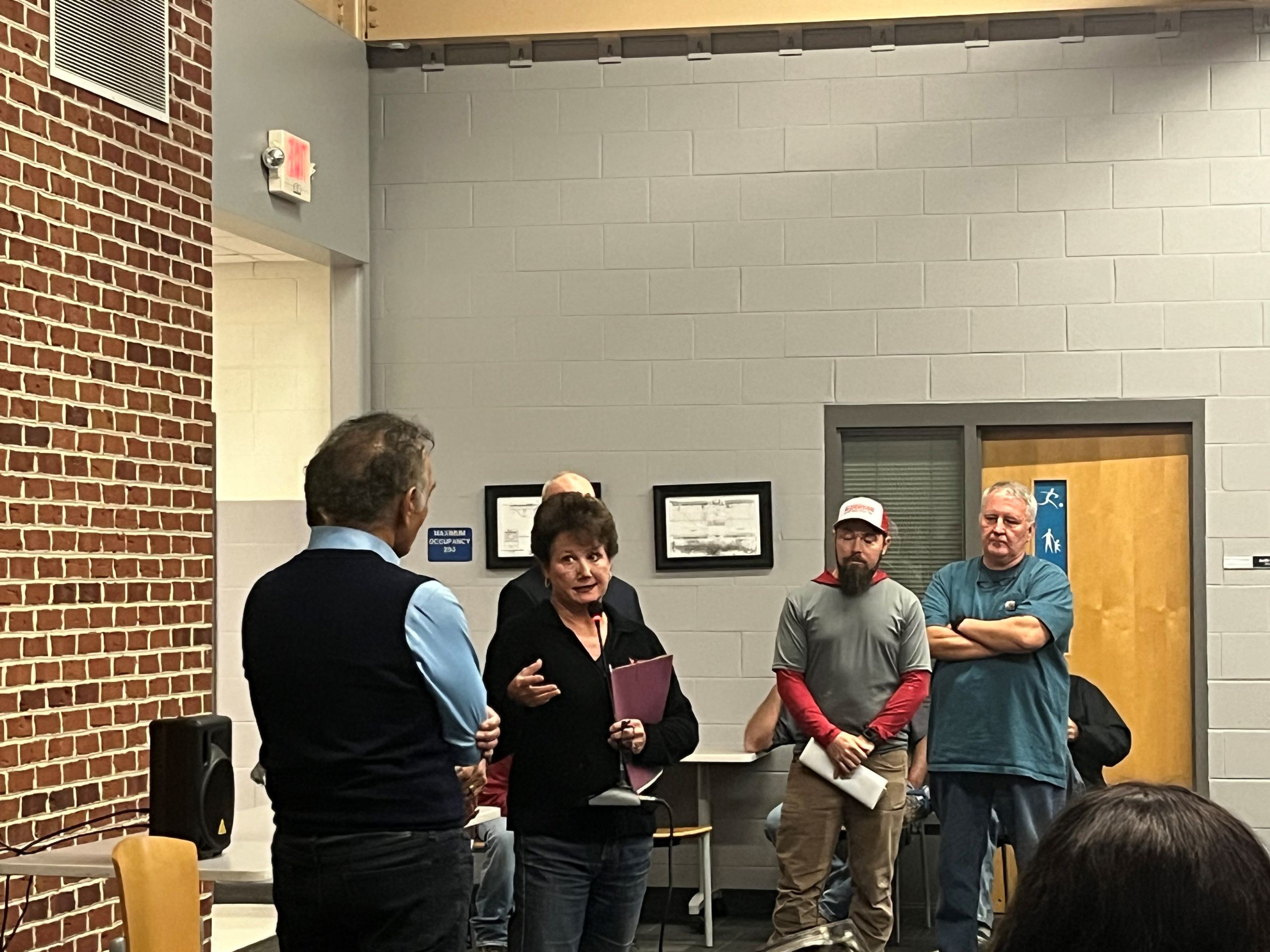 a woman with a microphone asks a man, Irfan Ali with Balico, a question at a Pittsylvania community outreach meeting