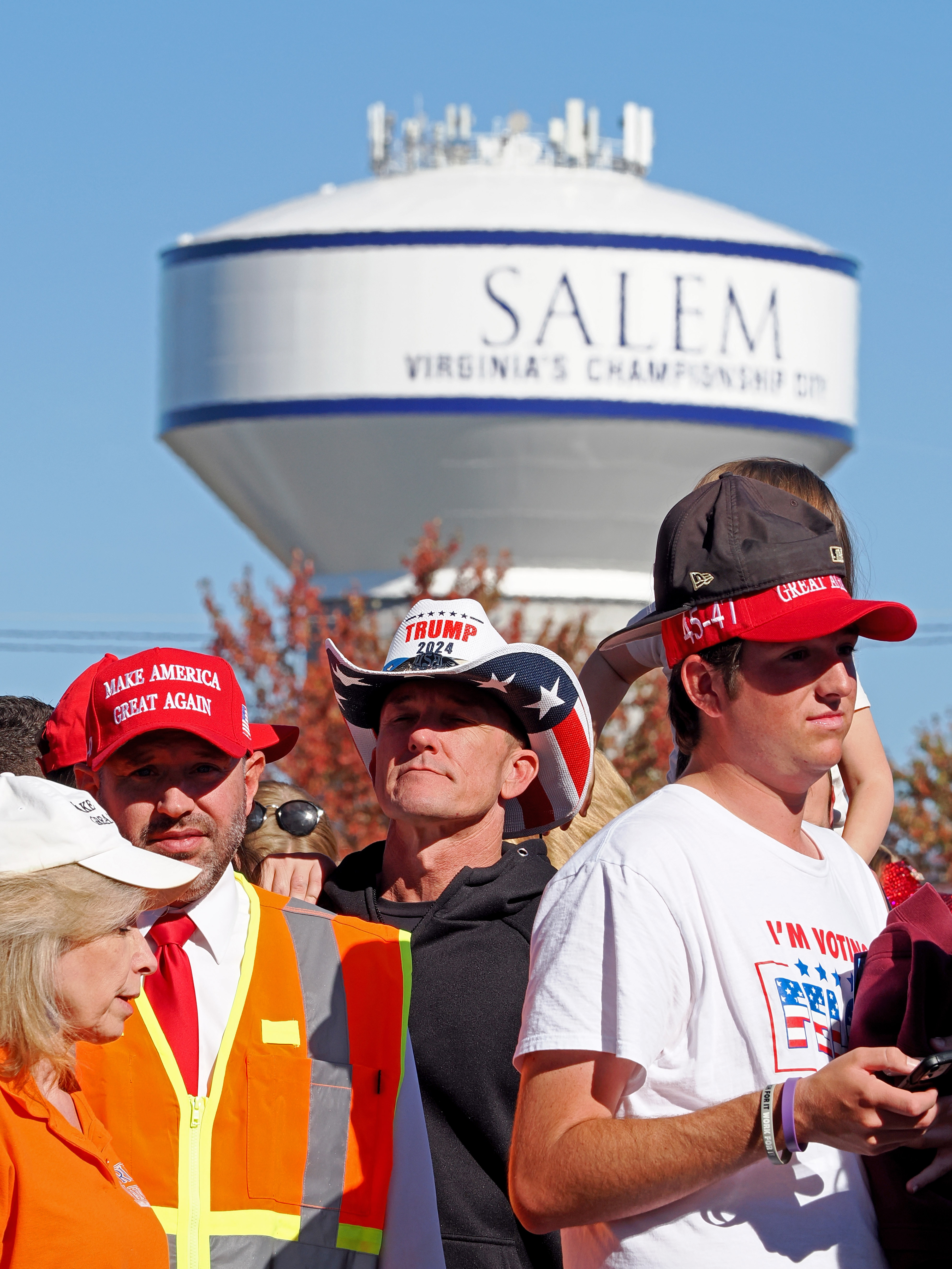 People supporting Donald Trump stand in front of a water tower with the word "SALEM" on it.