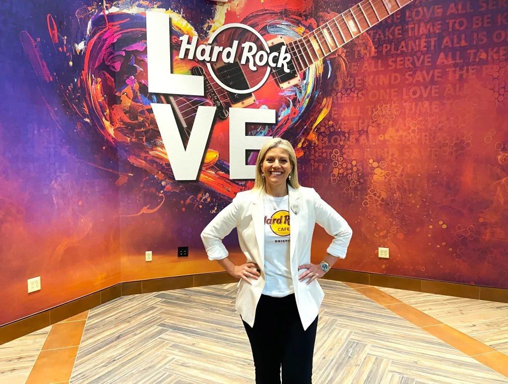 Allie Evangelista, president of Hard Rock Hotel & Casino Bristol, stands in front of Hard Rock wall inside the new casino.