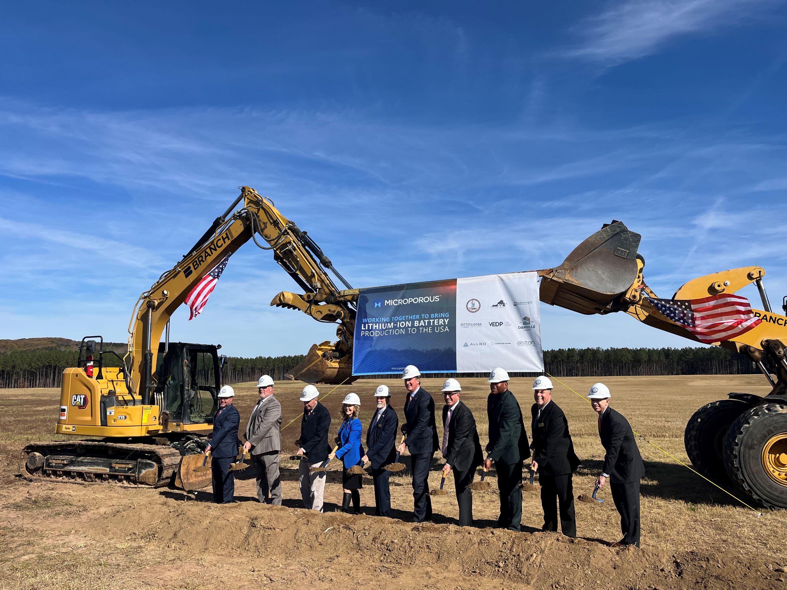 a group of people stand in front of bulldozers and a sign for Microporous at the Southern Virginia Megasite at Berry Hill.