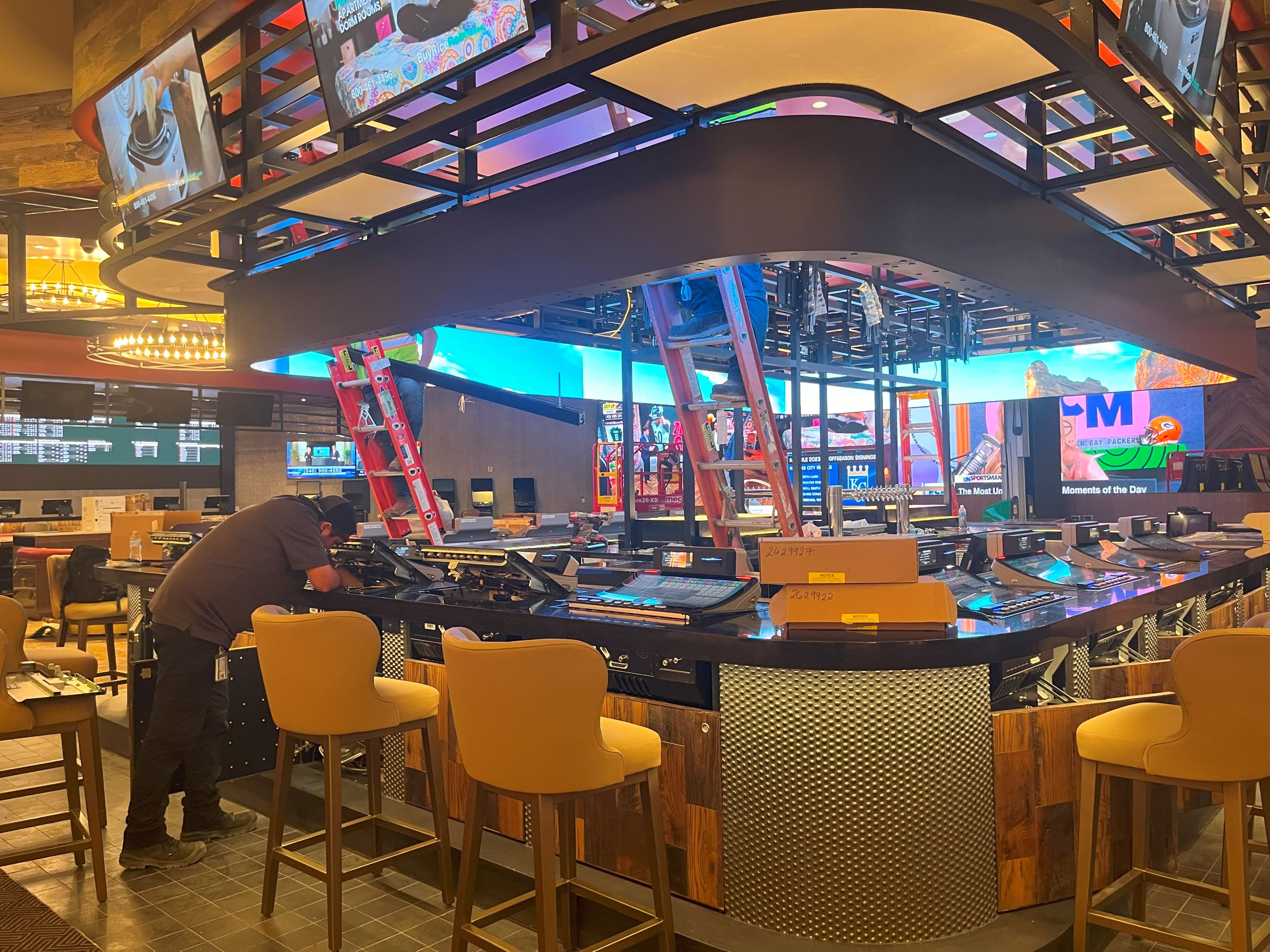 a Caesars Virginia employee repairs a display screen in the sports betting area of the casino.