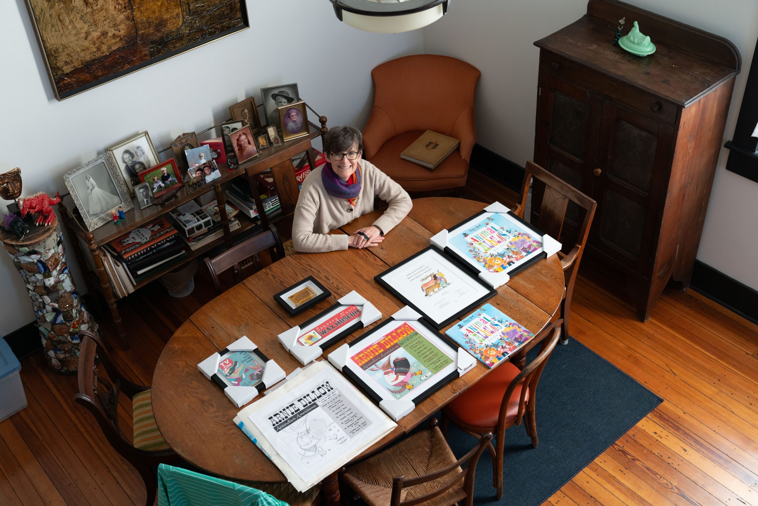 Cece Bellsits at a desk covered in her artwork