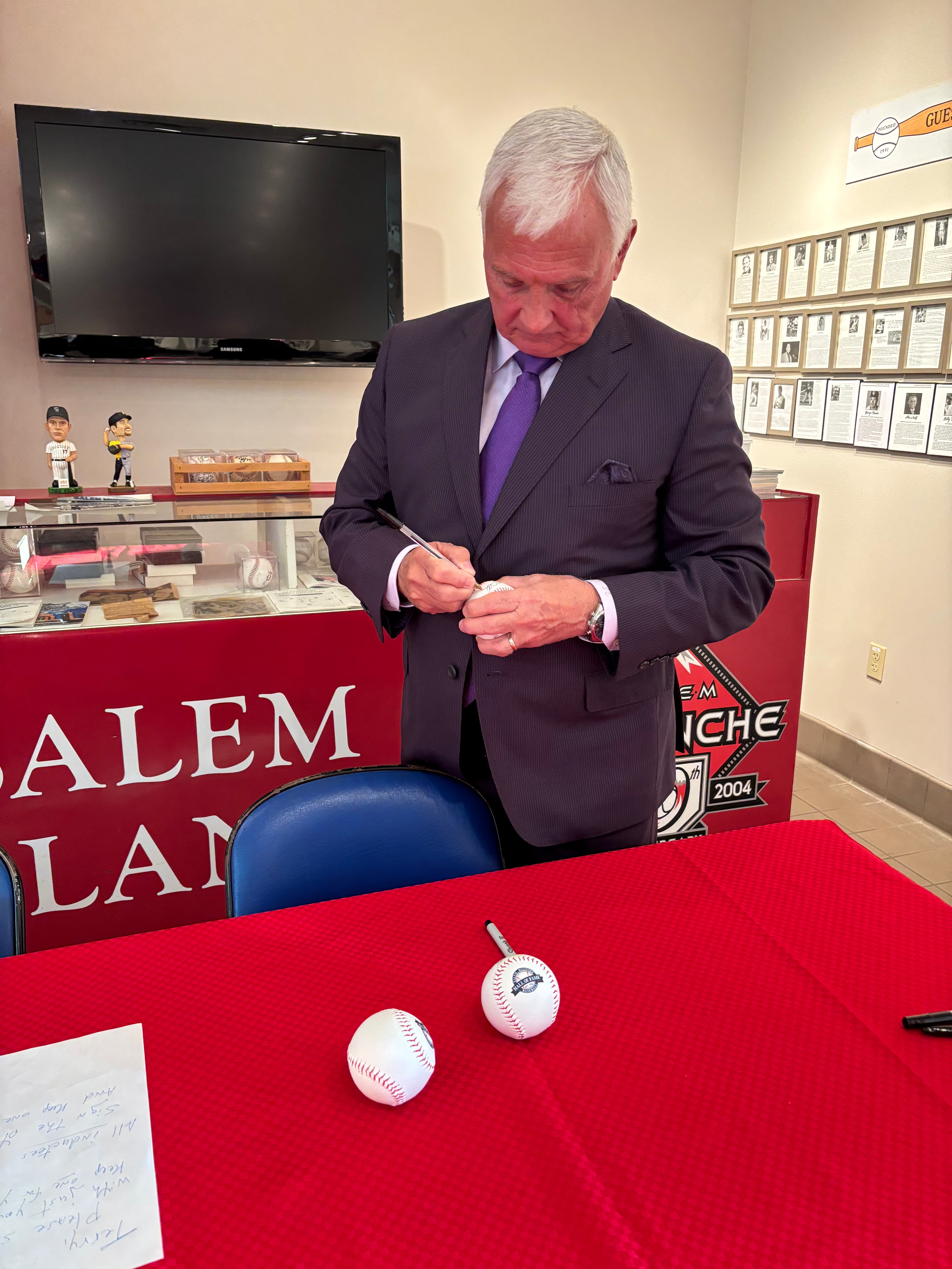 Terry Collins signs a baseball prior to his induction into the Salem-Roanoke Baseball Hall of Fame on Sunday, Feb. 2, 2025. Photo by Steve Hemphill. 