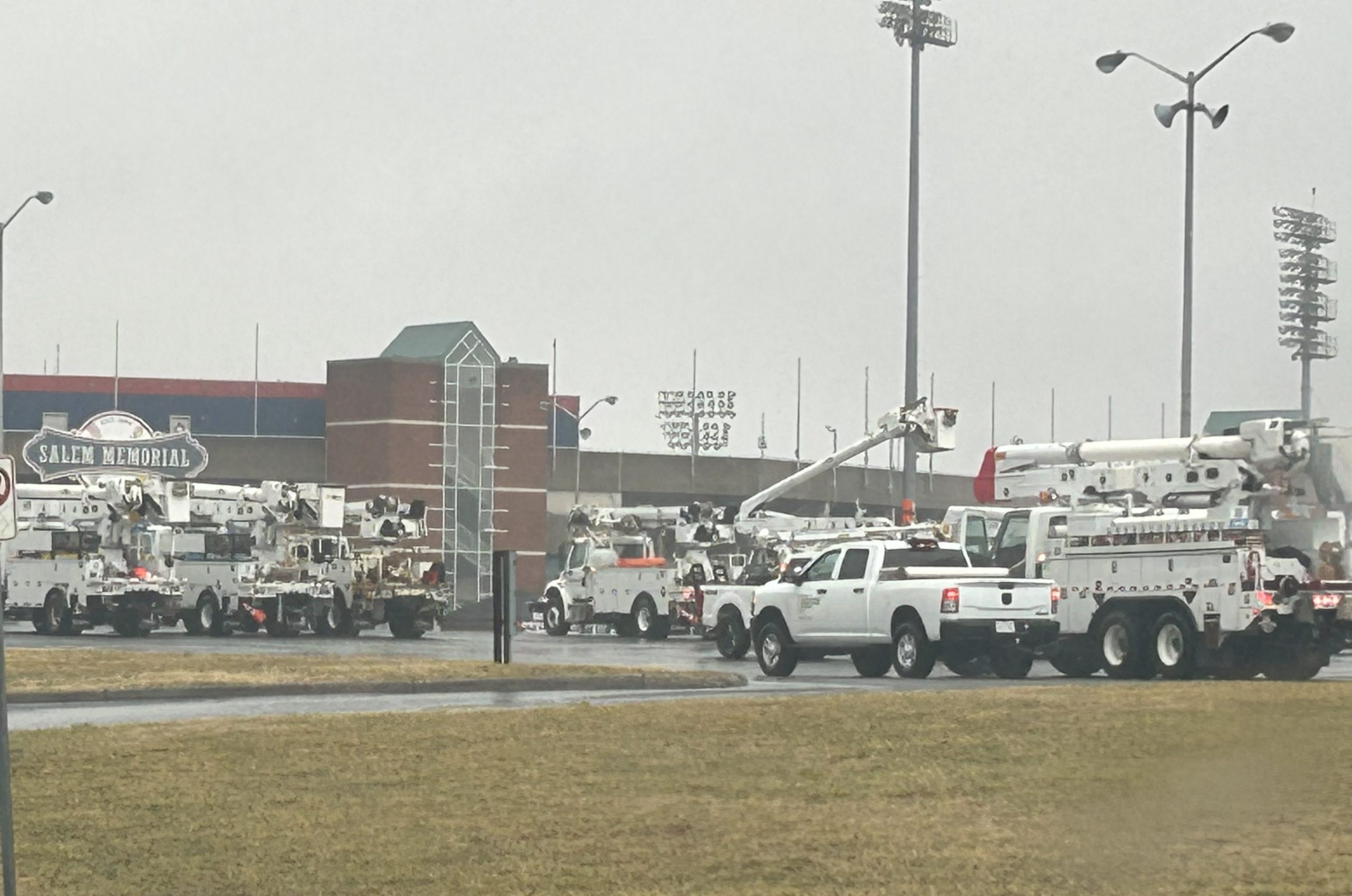 Utility and tree-clearing trucks stage in the parking lot of Salem Memorial Baseball Stadium on Sunday morning. Crews from multiple states have been hard at work restoring power in southern Virginia after last week's ice storm, but now face daunting new challenges with widespread tree and power line damage from strong winds later Sunday. Photo by Kevin Myatt.