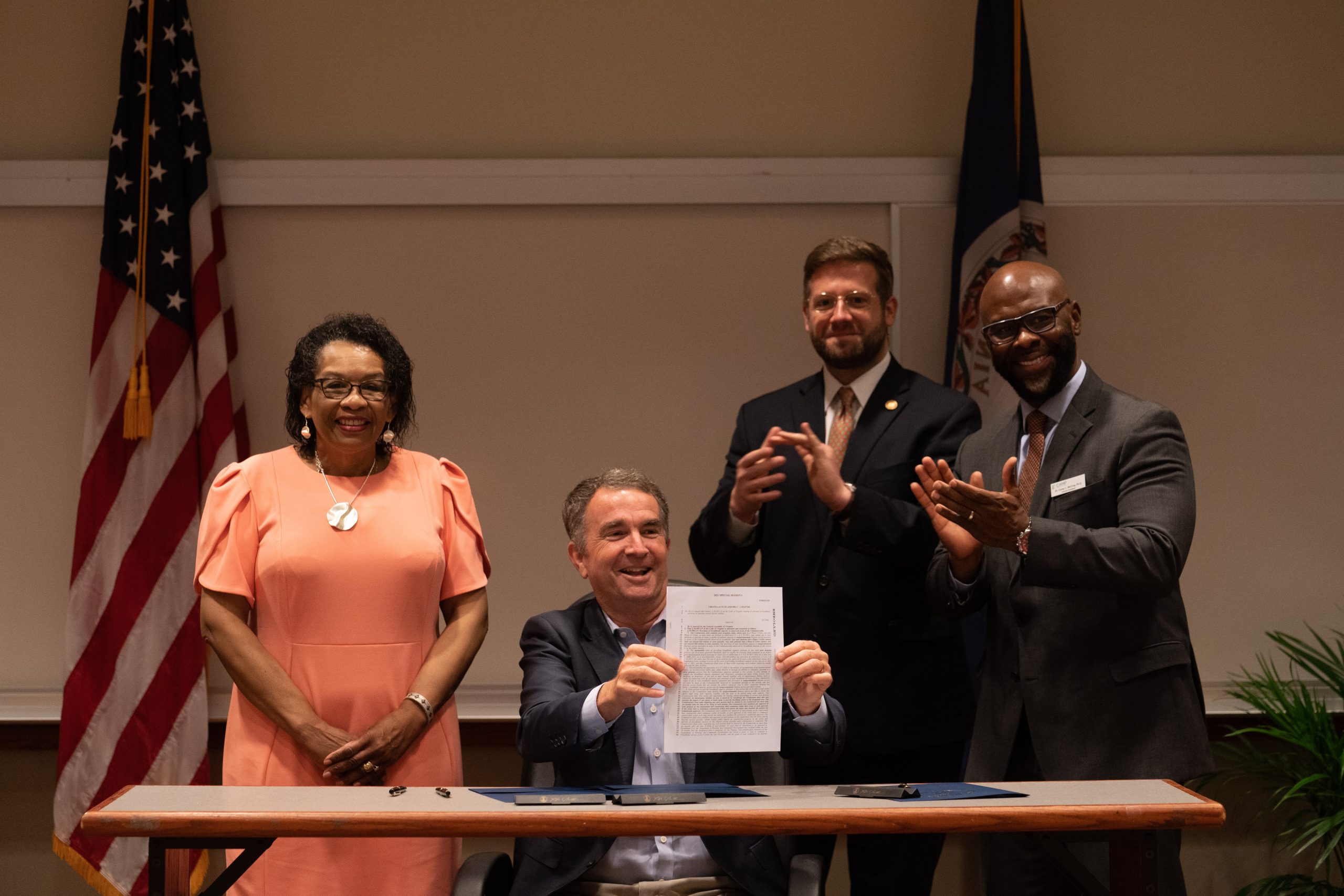 Gov. Ralph Northam (seated) signs a broadband expansion bill at Paul D. Camp Community College in Franklin in June 2021. With him are (from left) Del. Roslyn Tyler, who patroned the bill; Evan Feinman, the governor’s chief broadband adviser; and Corey McCray, the college's interim president.