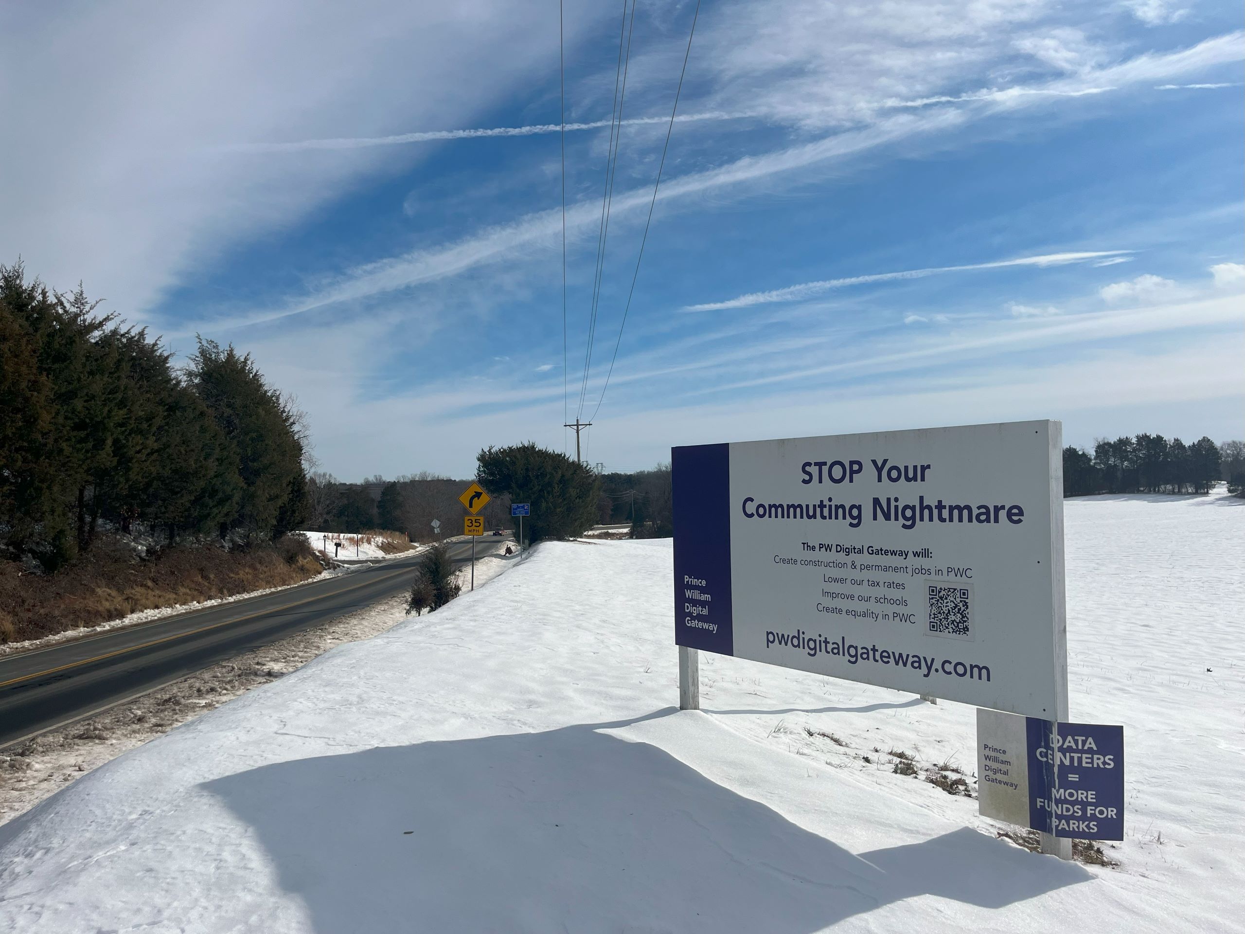 along a rural backroad in Prince William County, a large sign advertising the Digital Gateway data center is placed in a snowy embankment