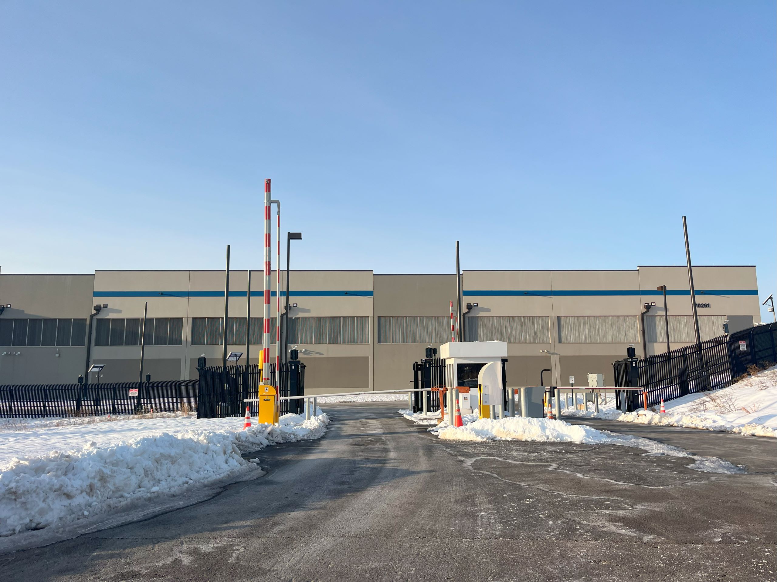 A large, gray building with a security booth outside, the Amazon Tanner Way data center