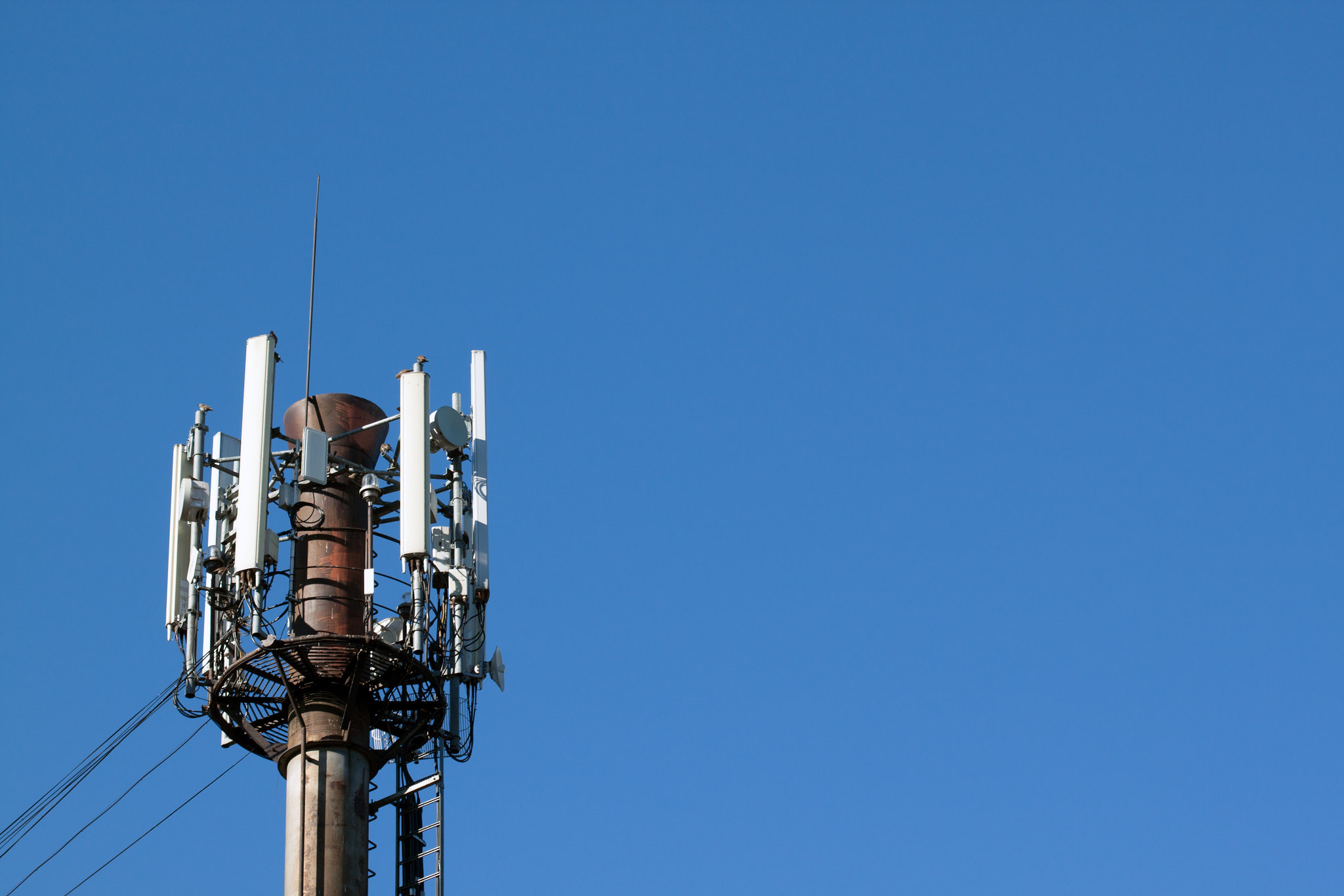 The top of a cell tower against a blue sky.