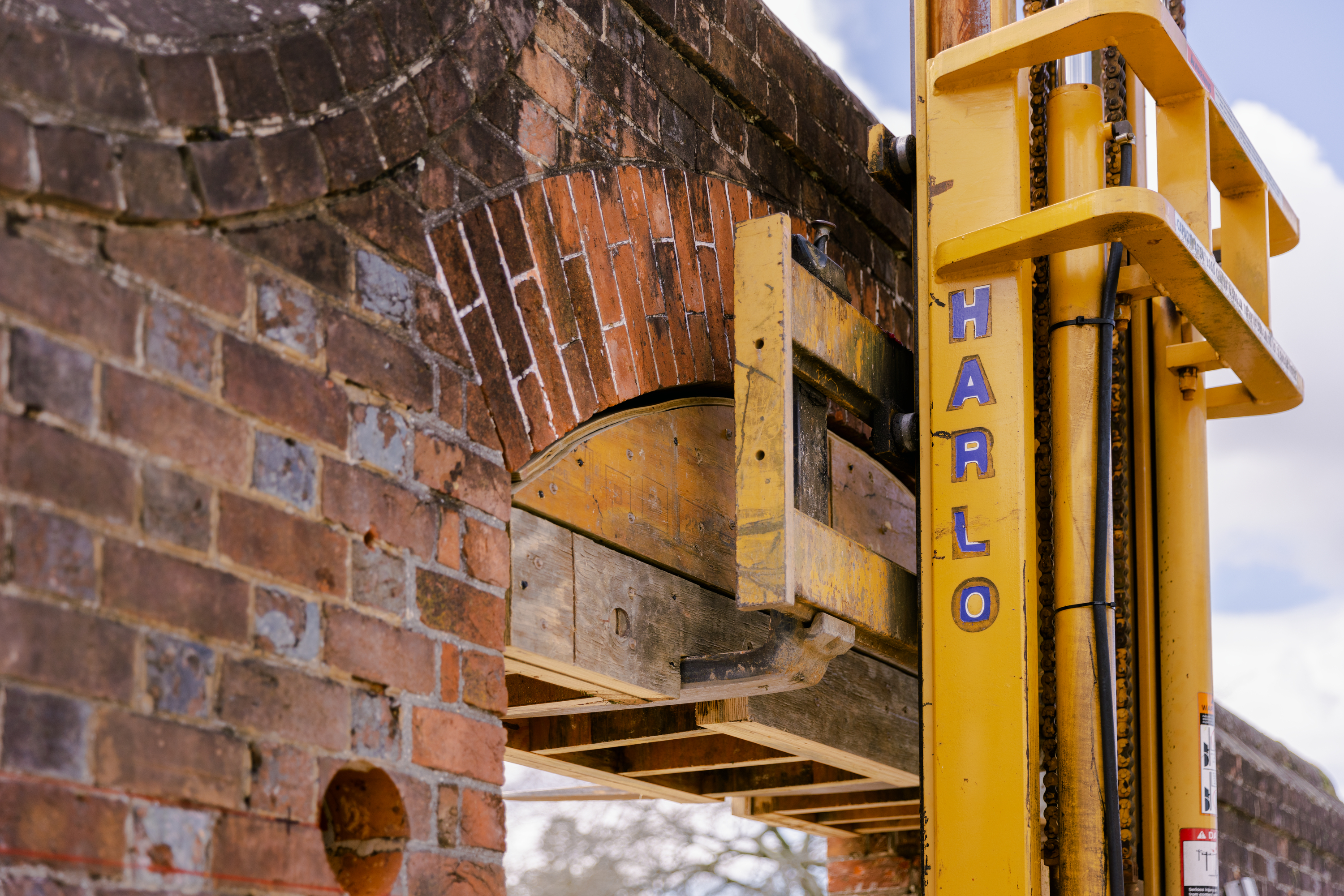 A forklift places a wooden brace for the gate arch in the Magazine's outer wall prior to the arch's removal. March 7, 2024. Credit: Brendan Sostak, The Colonial Williamsburg Foundation