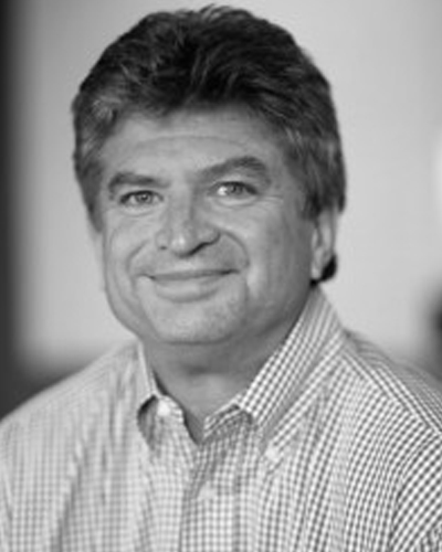 Head shot of the late Bonz Hart. He is wearing a checked, button-down shirt in the black-and-white photo, in front of a indistinct background.