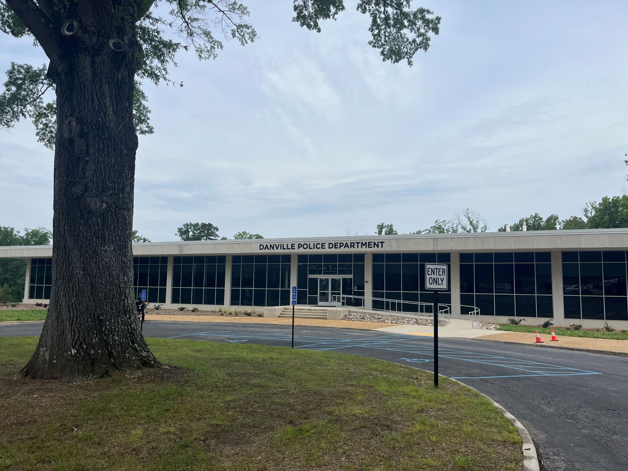 a concrete and glass building, the Danville Police Department, with a large tree in front and to the left of the frame