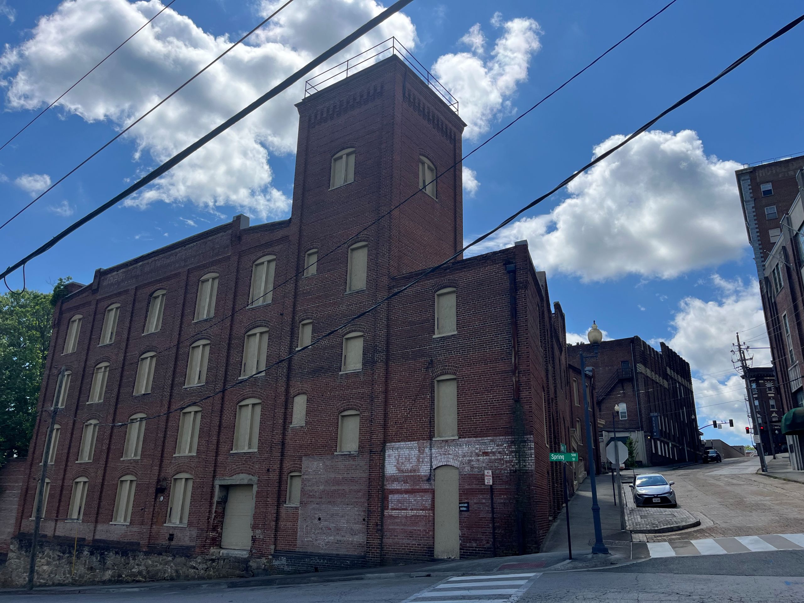 A large brick building with boarded up windows stands vacant on the corner of the street in Danville's River District
