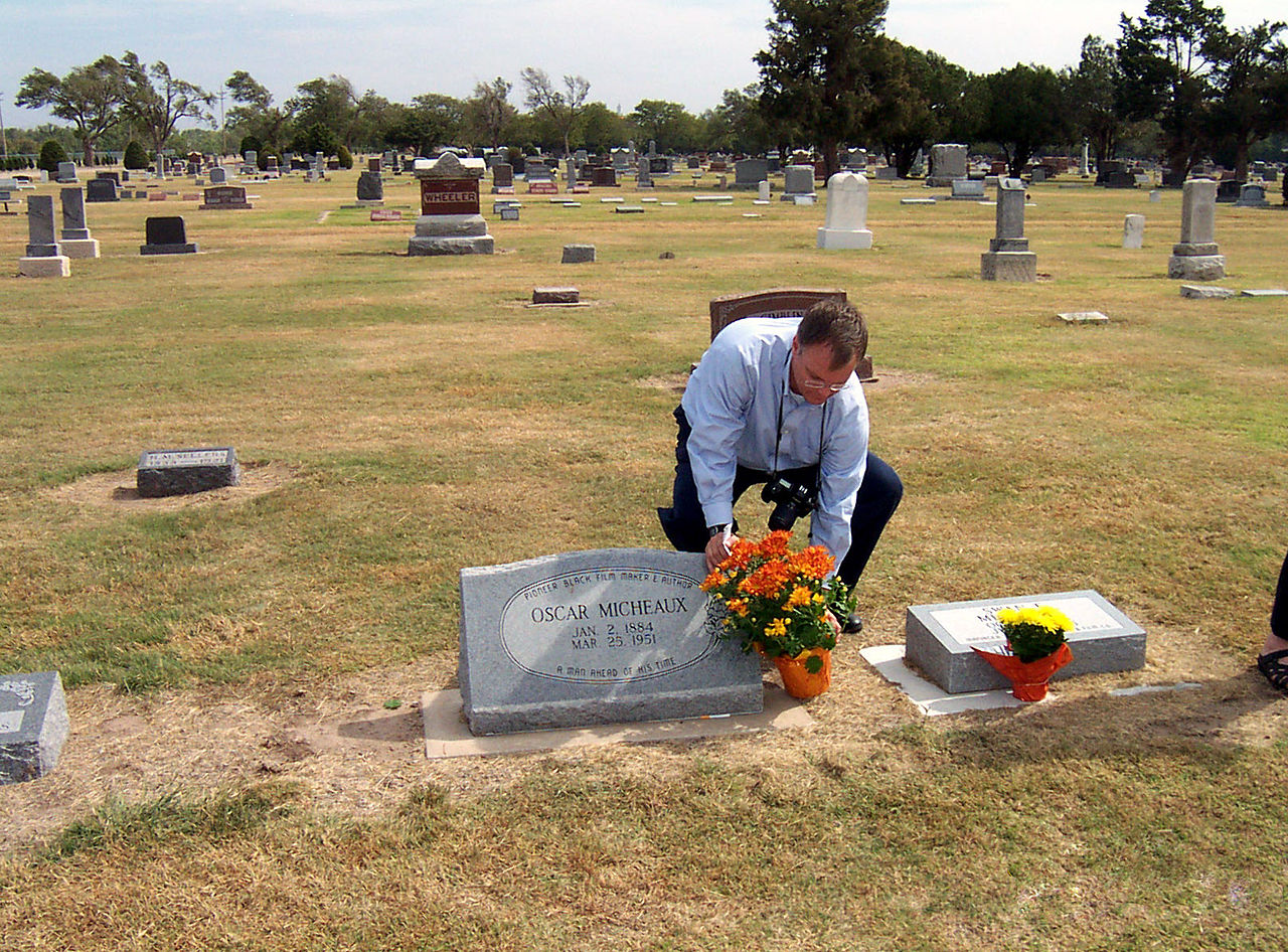 An unidentified admirer places flowers on Oscar Micheaux's grave in Great Bend, Kansas during a film festival in his honor in 2005. Courtesy of Pommrencke. 