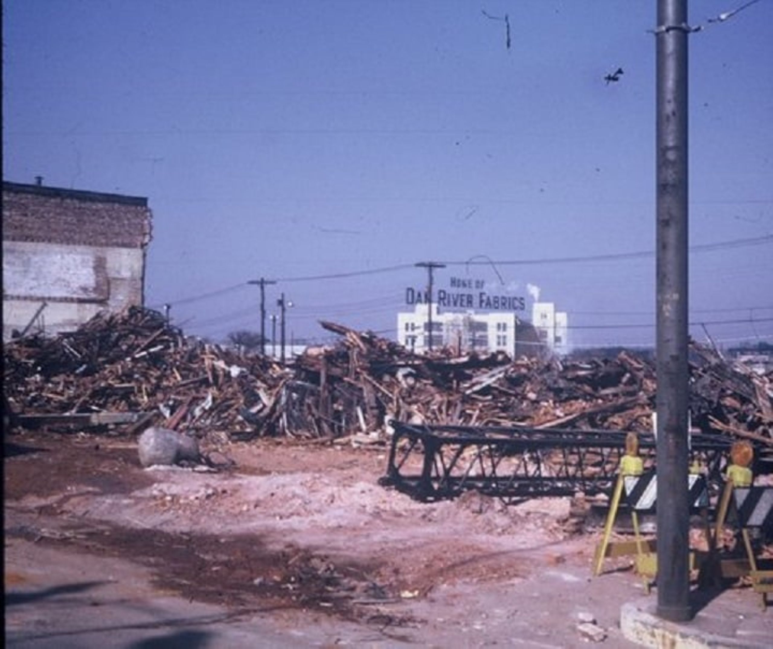 debris from demolishing buildings is piled up with Danville's White Mill in the back, topped with the iconic Home of Dan River Fabrics sign