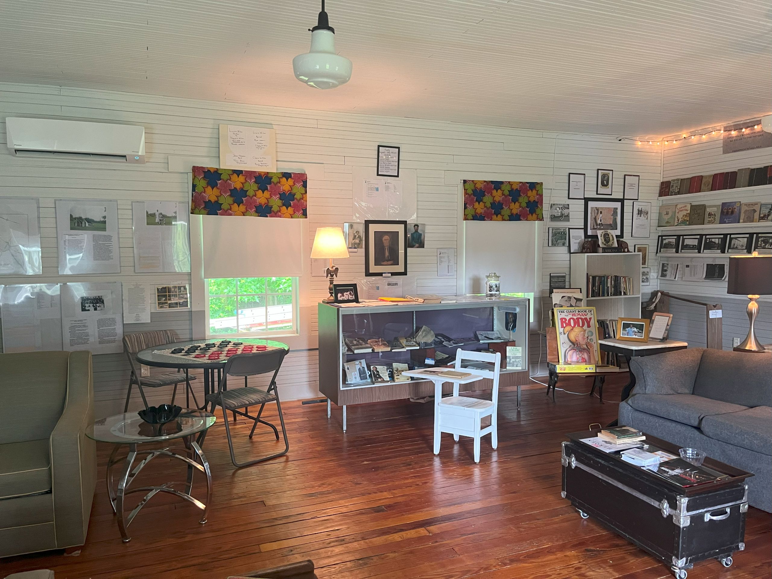 a room with white walls, decorated with picture frames. This is the interior of the Harvey Schoolhouse