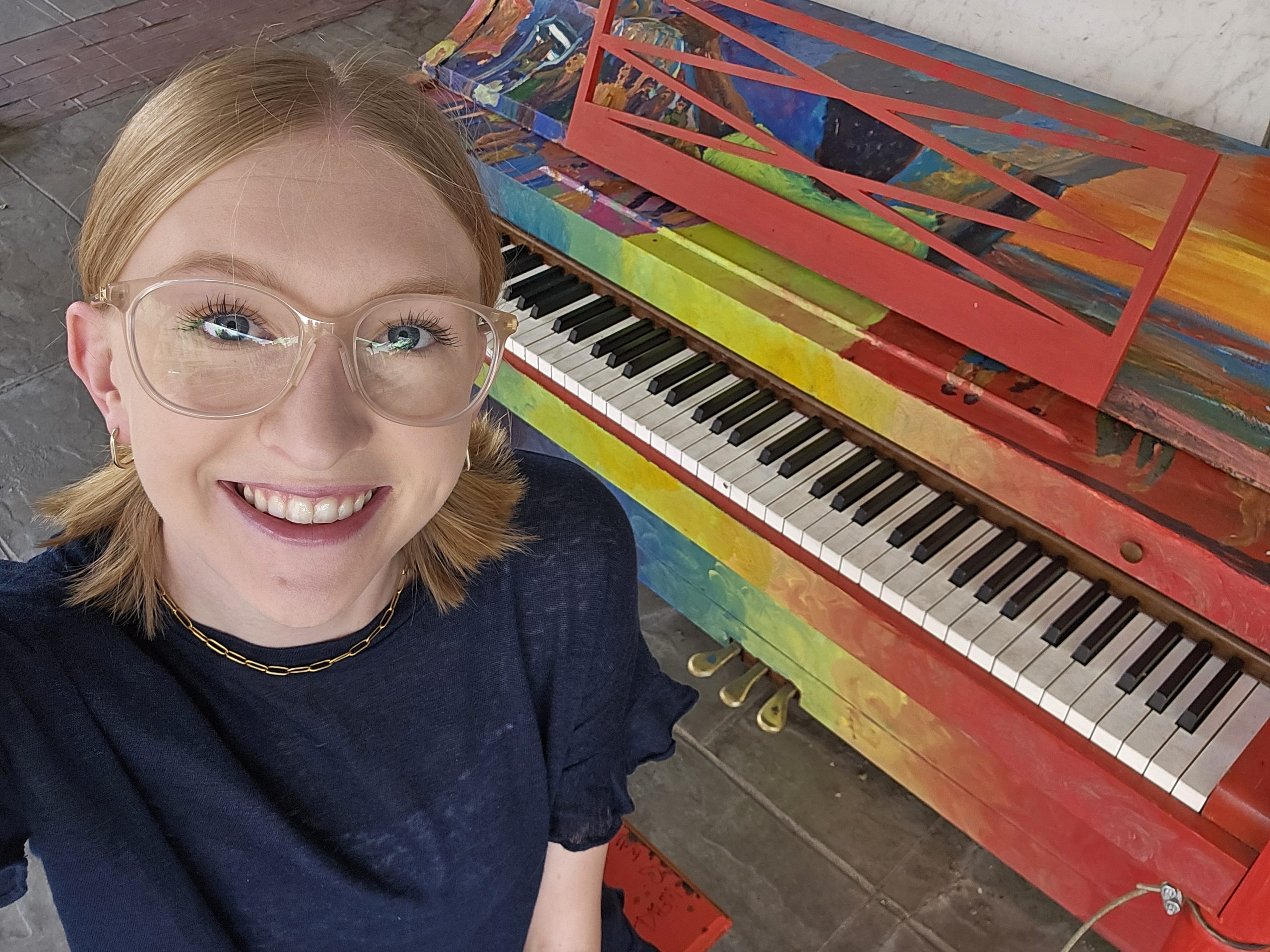 Reporter Emma Malinak stands beside a well-known colorfully painted piano in Lynchburg, Va.