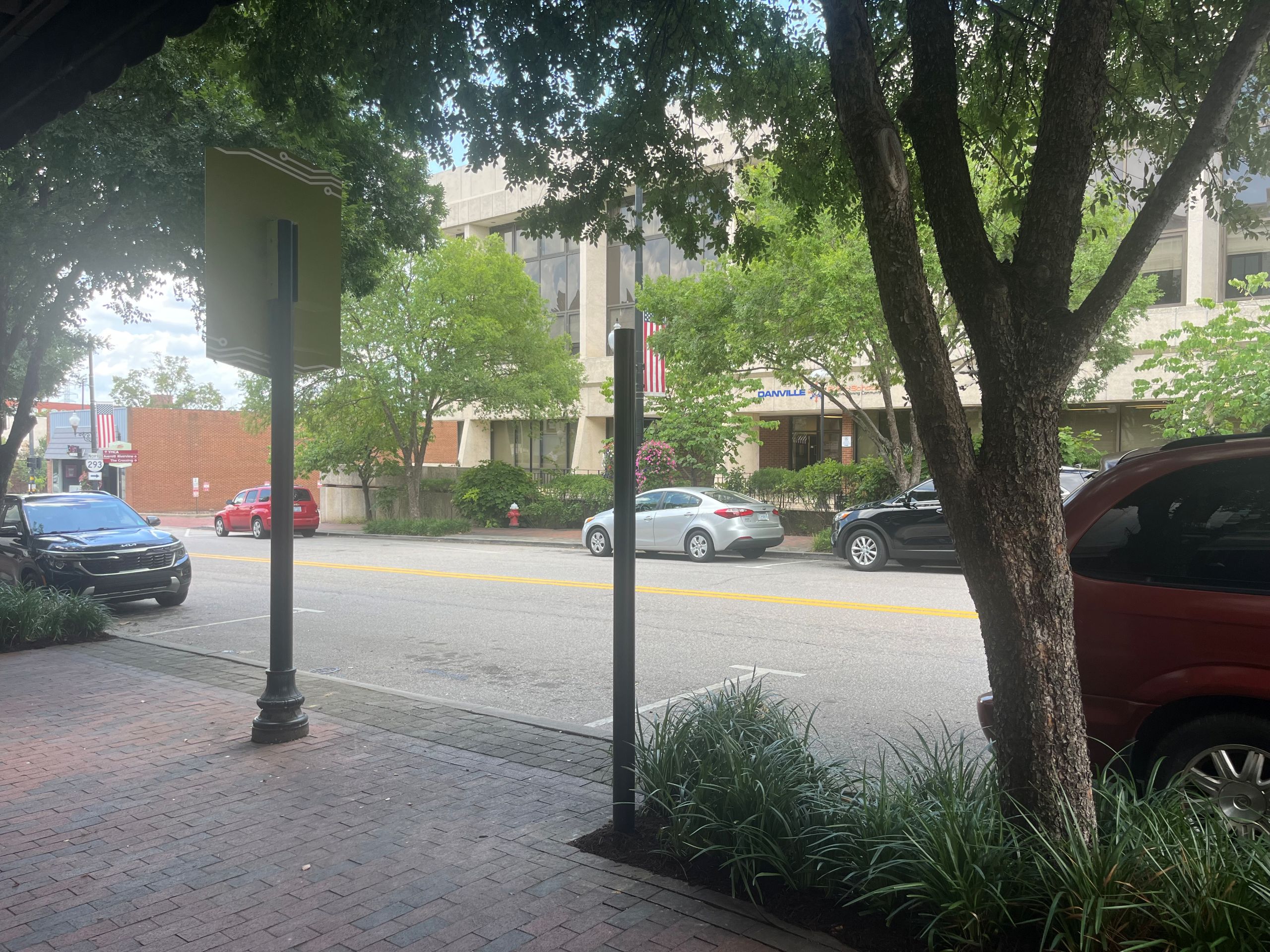 The brick sidewalk of Main street in Danville's River District, where a black post stands, waiting to be topped with a historic marker