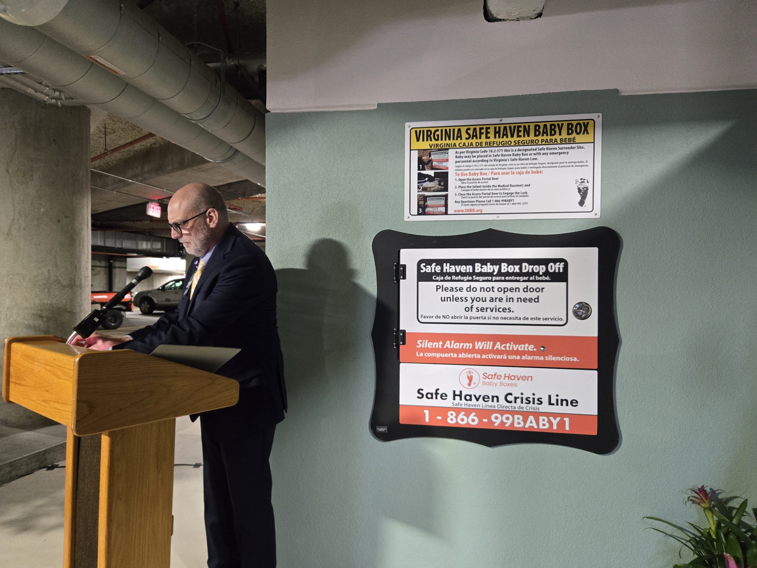 Keith Little, a chaplain at Carilion Roanoke Memorial Hospital, stands to bless the new Safe Haven Baby Box on Tuesday, July 8. The box, positioned on an exterior wall in the emergency department parking garage, provides a place where parents can anonymously surrender a newborn baby without legal repercussion. Photo by Emily Schabacker.