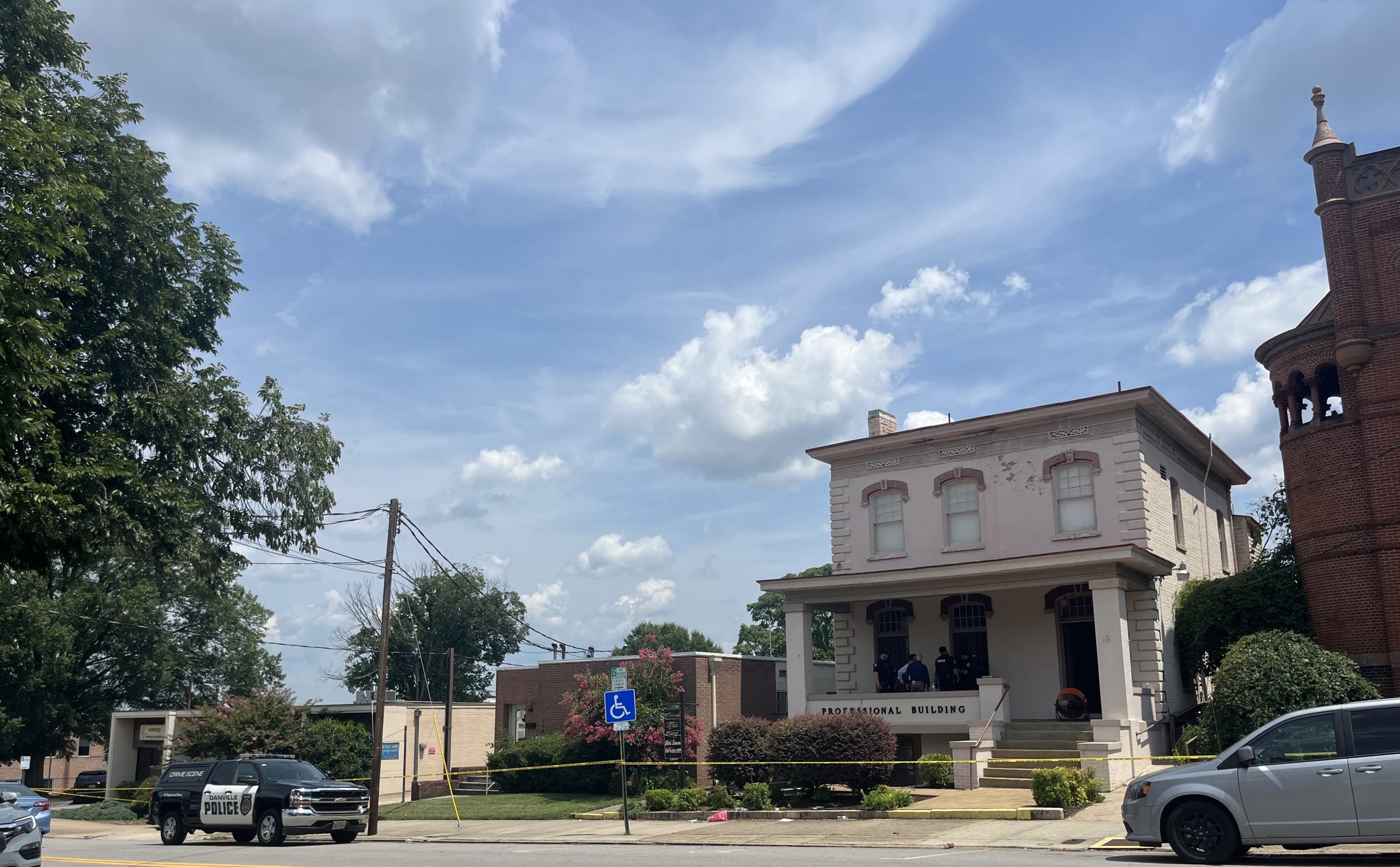 The exterior of Showcase Magazine's offices a two-story painted brick building with a front porch and a police car parked outside.