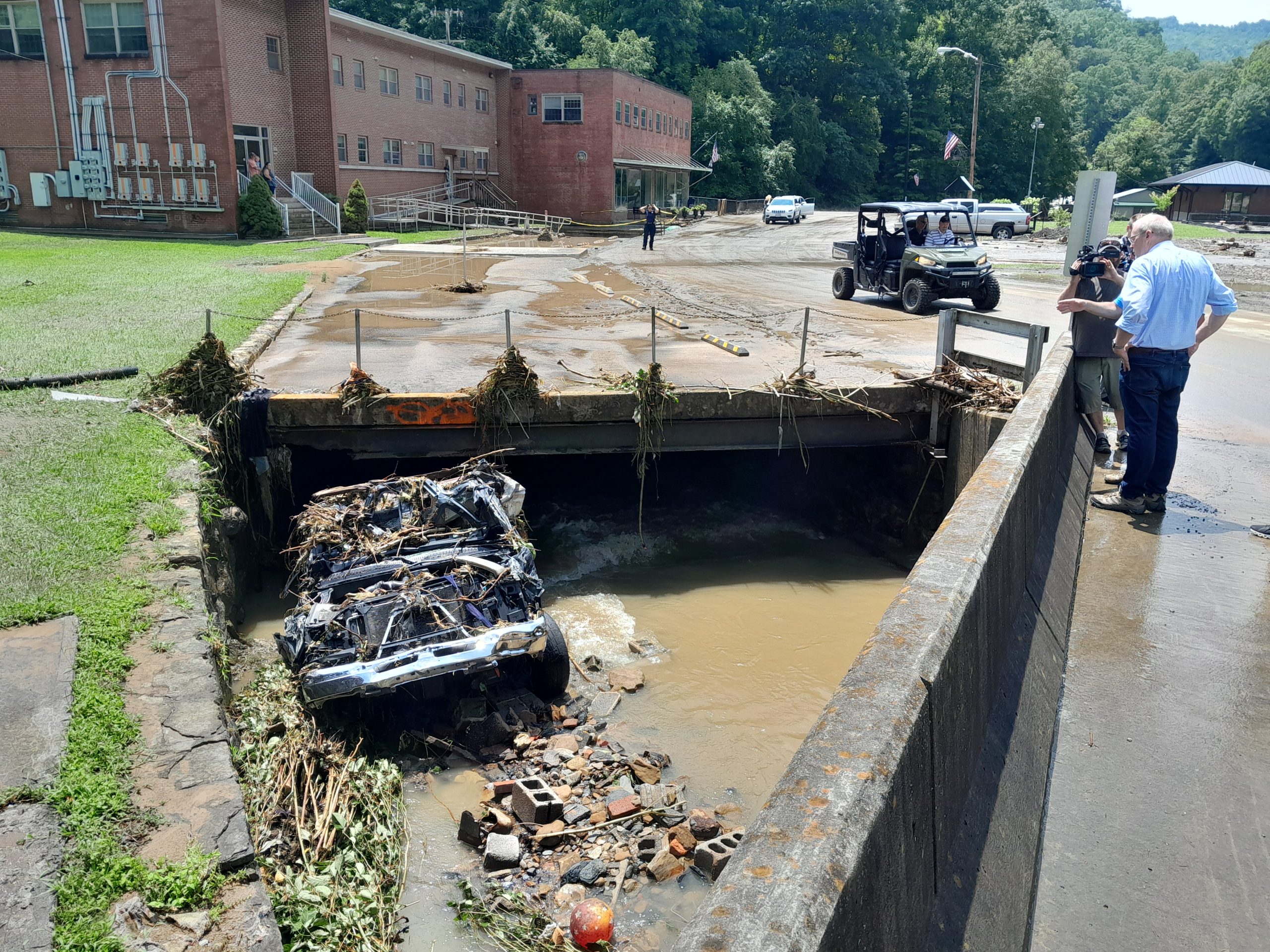 Rep. Morgan Griffith looks down at a pickup truck that floated away during Friday’s flooding in Dante and got stuck in this culvert. Its driver and a passenger floated downstream outside the vehicle and were rescued. Photo by Jeff Lester.