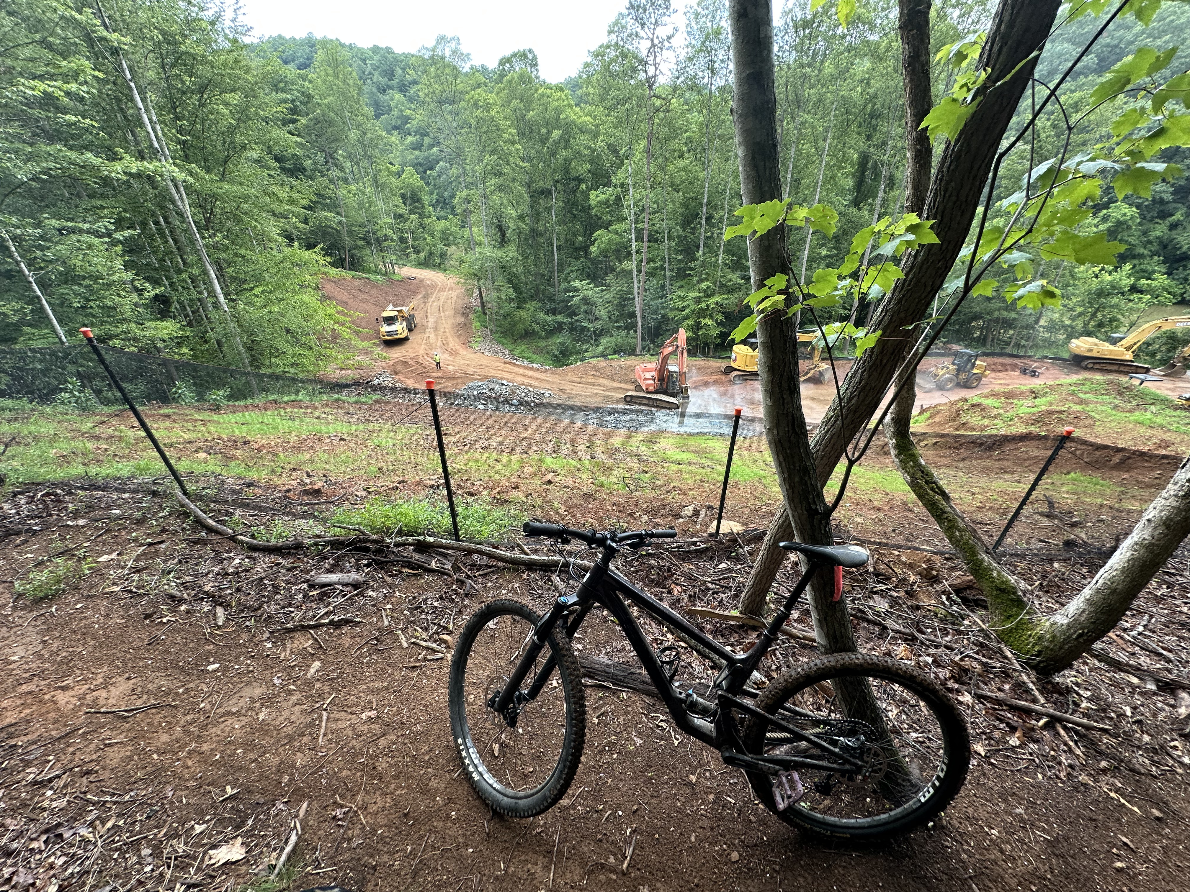 a bike parked on a dirt trail, with a construction zone in the background