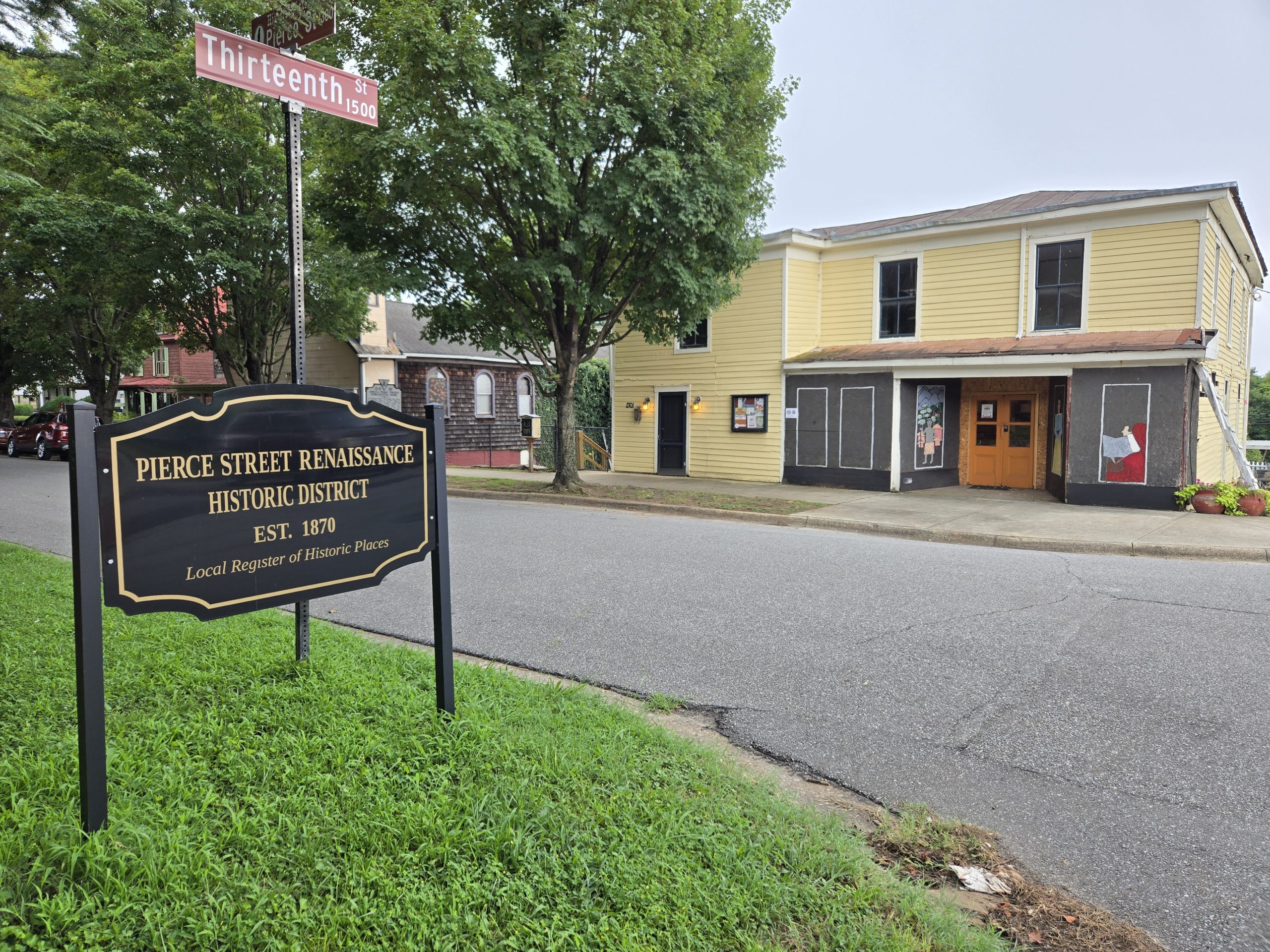 A yellow grocery store sits across the street from the "Pierce Street Renaissance Historic District" sign.