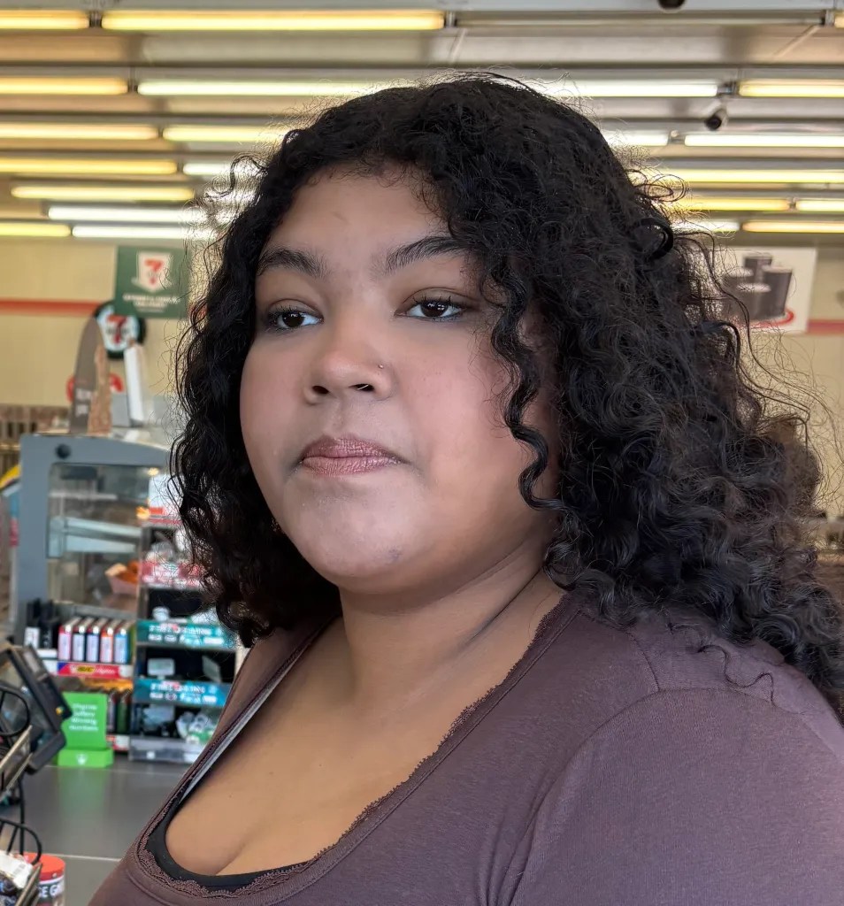 Mug shot of 7-Eleven shopper Sophia Boyd, standing in front of the store counter.