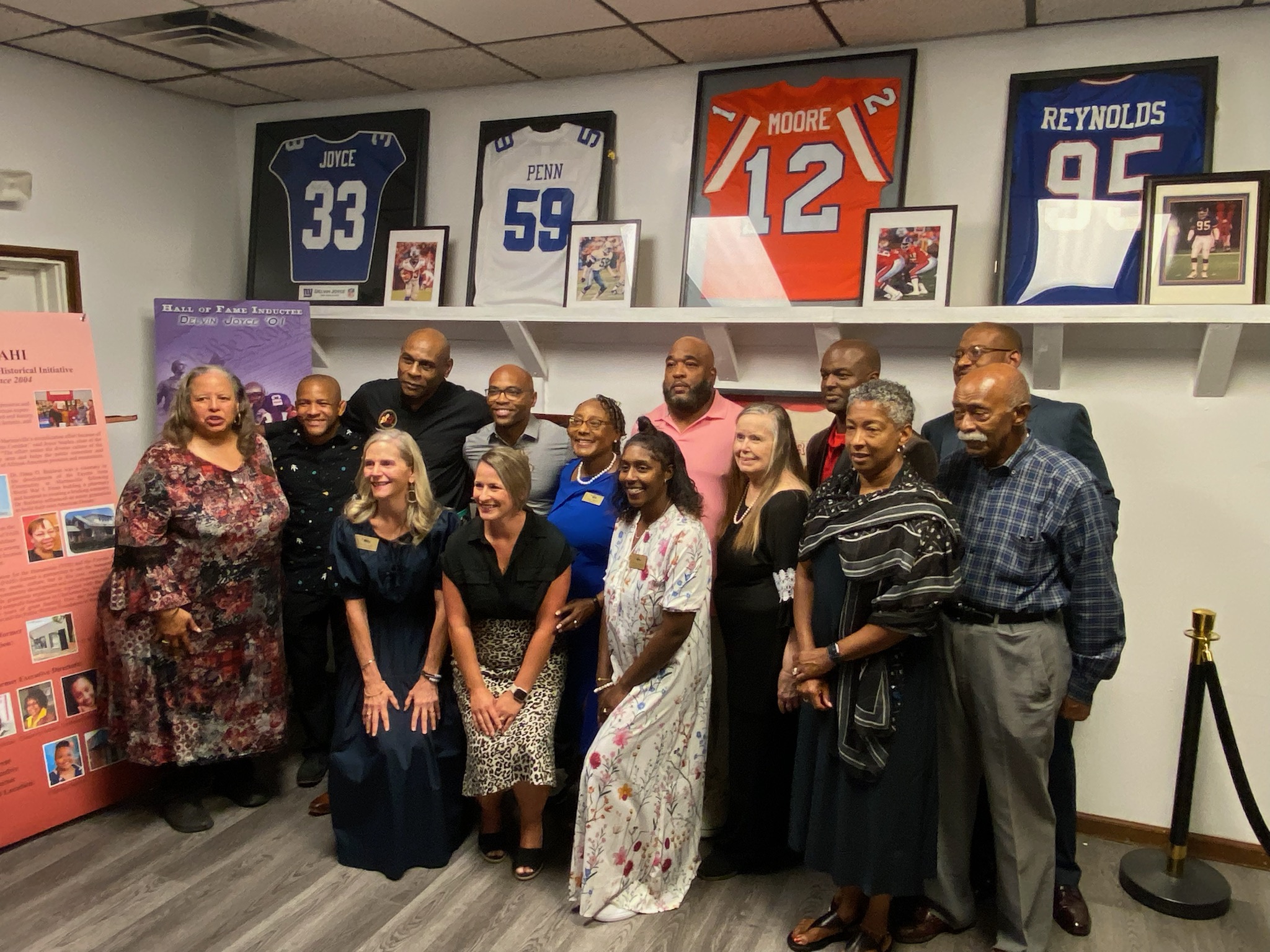 Members of FAHI board of directors and several former athletes pose in front of NFL jerseys in the exhibit hall. Photo by Robert Anderson