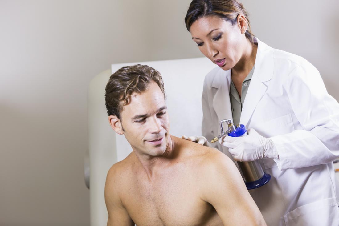 physician performing cryotherapy on man's shoulder