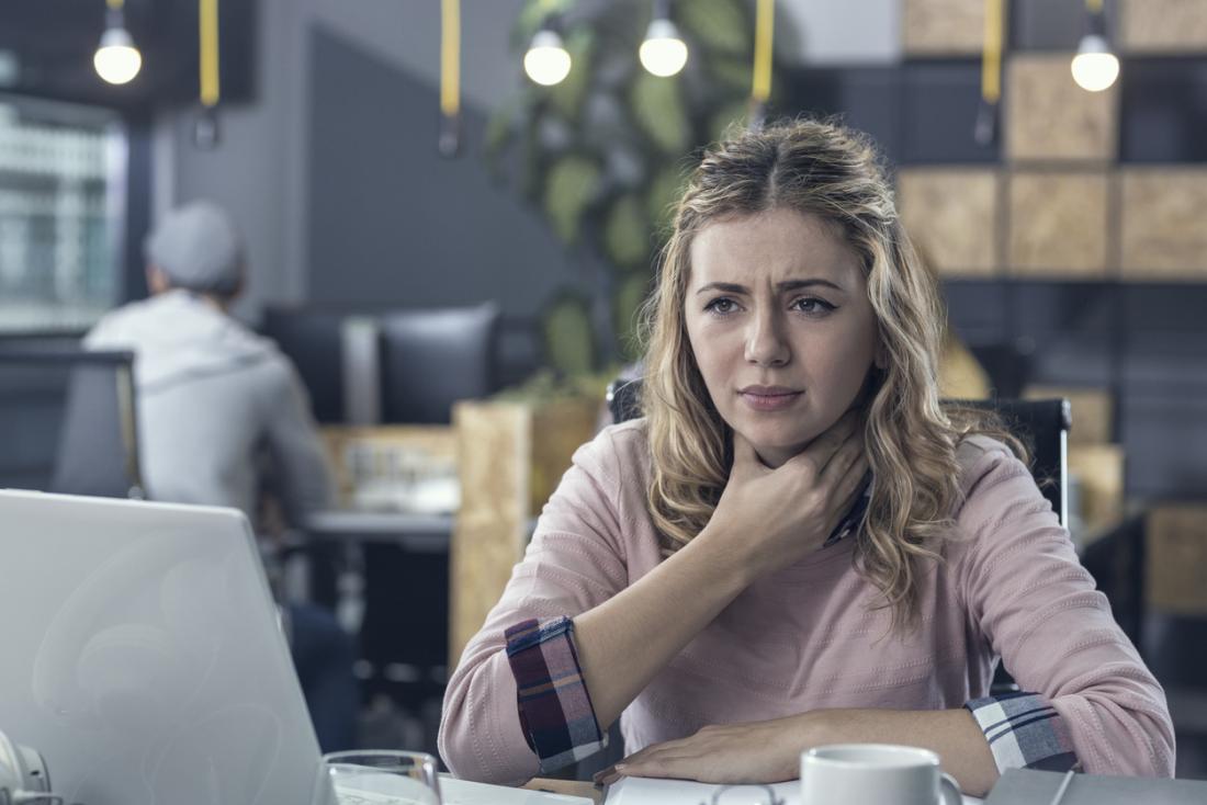 Woman with sore throat pain at work.