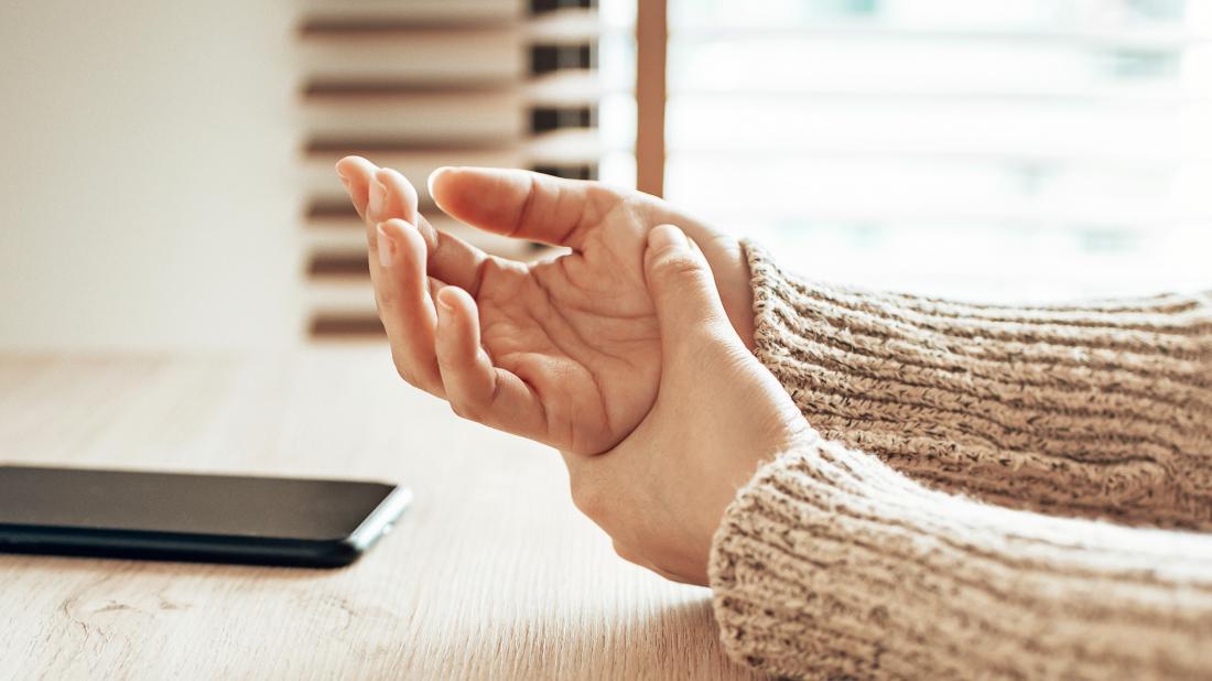 a person holding one their hands as they are experiencing numbness there 