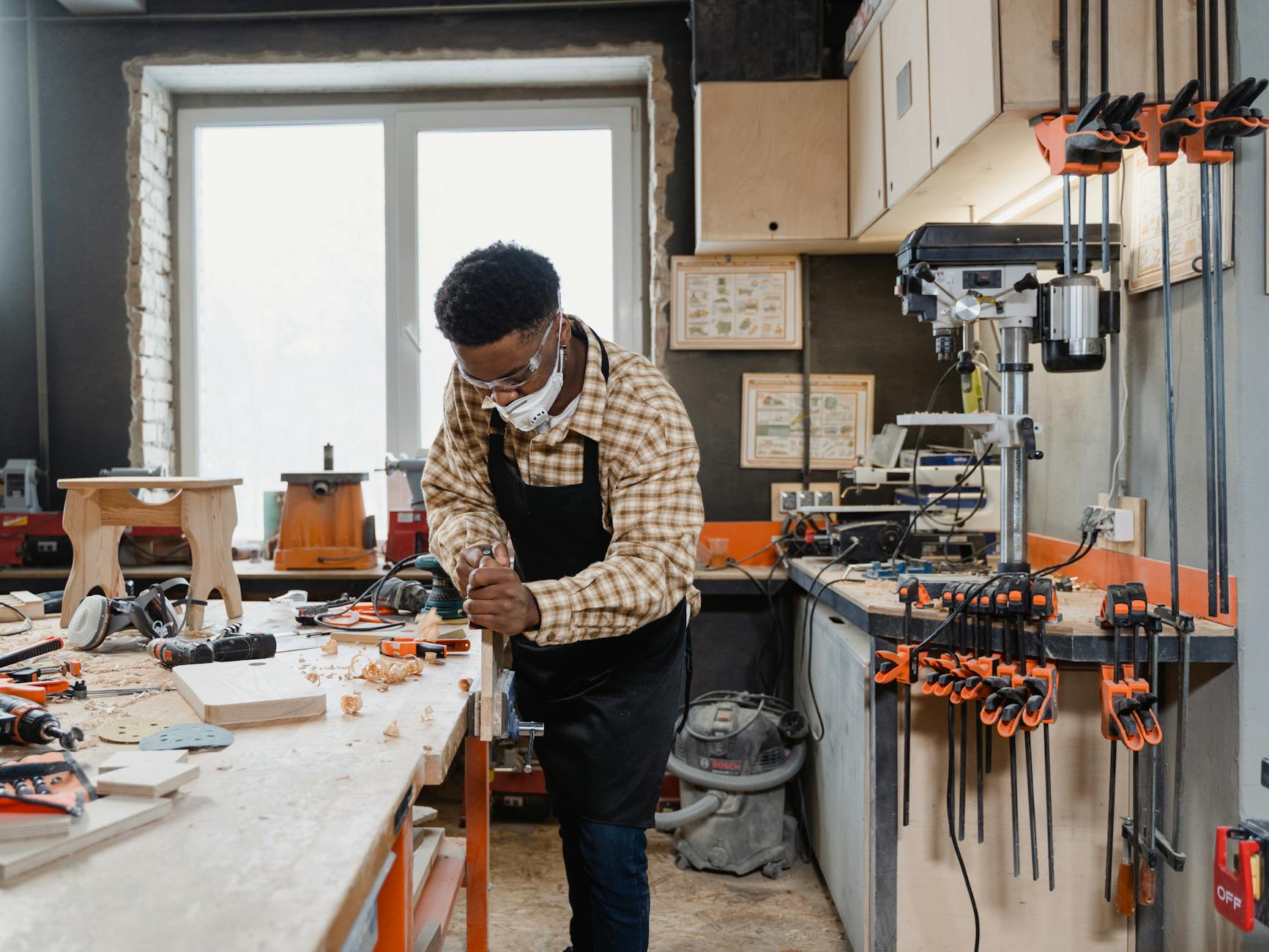 man in plaid long sleeves carving wood