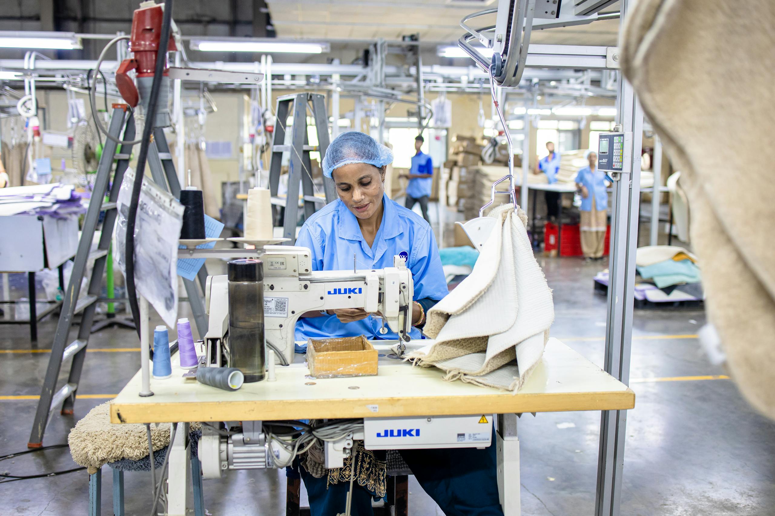 FLAIROC GHANA Textile factory worker sewing fabric using Juki machine in industrial setting. CETECH Ghana