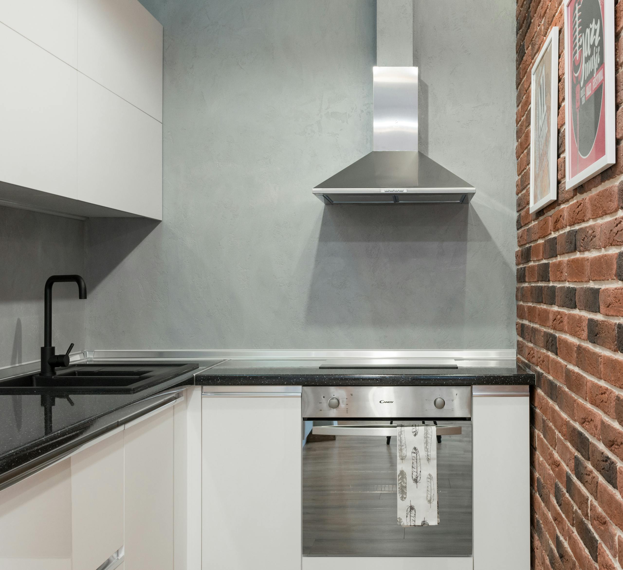Contemporary kitchen interior with stainless steel appliances and brick wall.