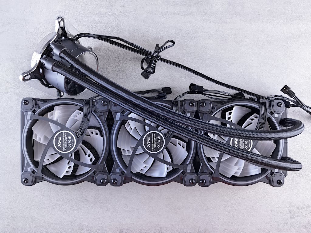 Top view of a triple radiator cooling system with fans for computer hardware in a minimalist gray setting.