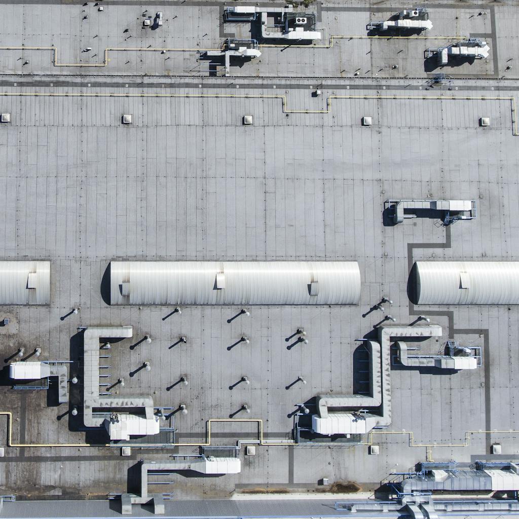 Aerial top view of a factory roof showcasing industrial pipes and structures.