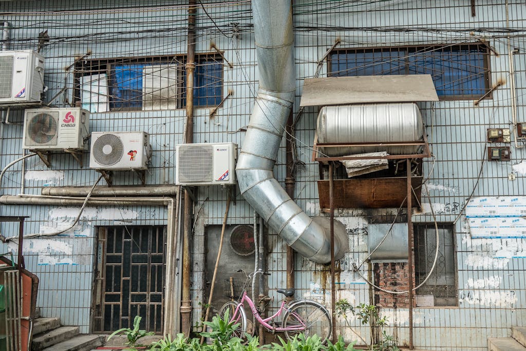 An urban building facade featuring multiple air conditioning units and ductwork.