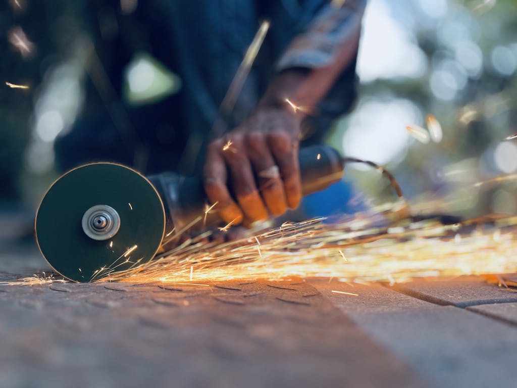 Dynamic shot of a man using an angle grinder with sparks flying. Perfect for industrial themes.