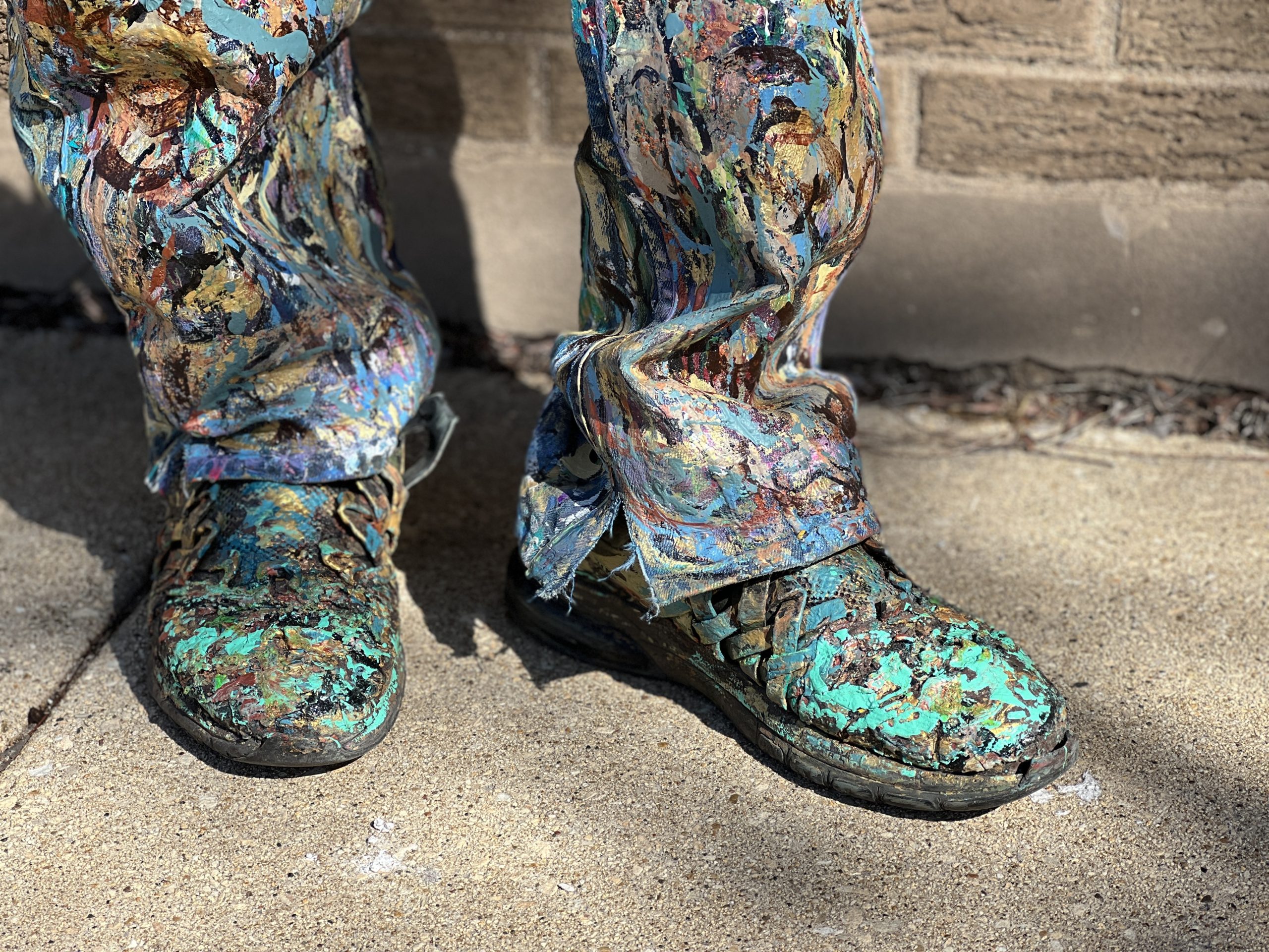 A close up shot of George Blakemore's paint-bespattered work boots, and the bottom cuffs of his matching jeans