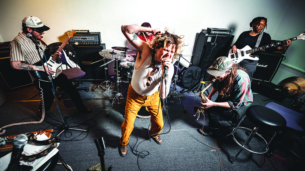 Five members of punk band Edging play in their rehearsal space, crowded together by the small room