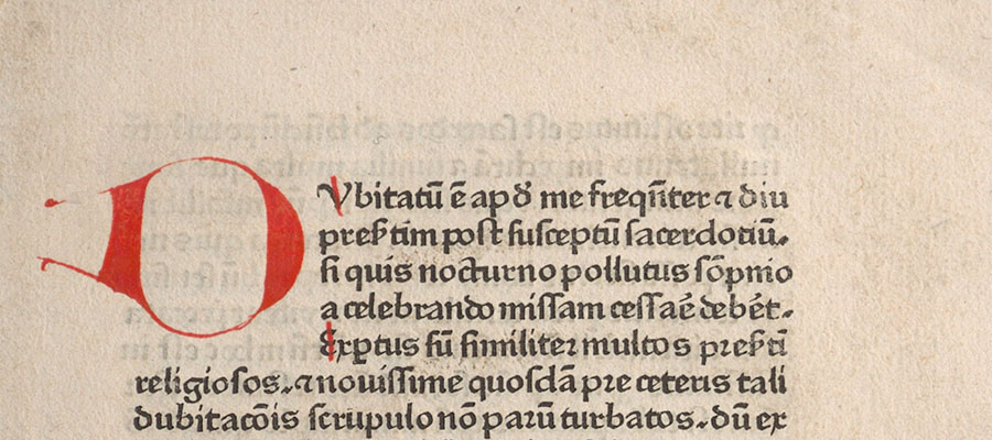 Detail from a printed page in Latin in one column with handwritten initial letters in red.