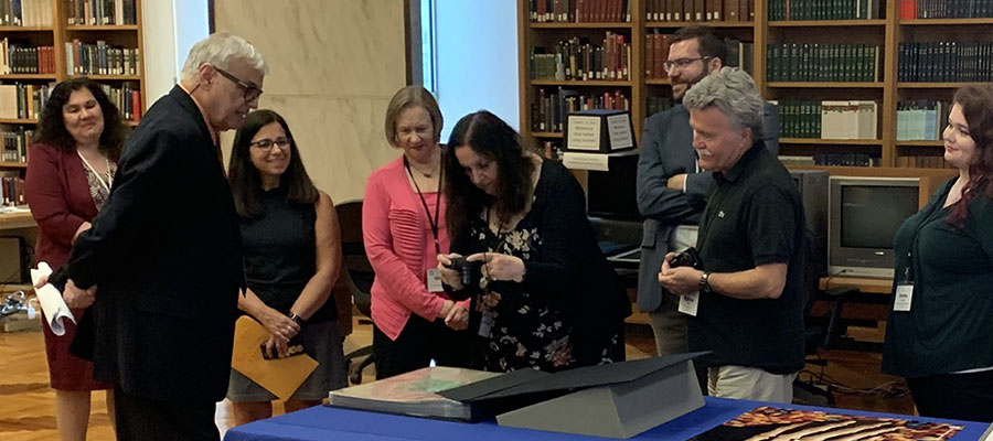 A group of people stand around a display of books on tables.