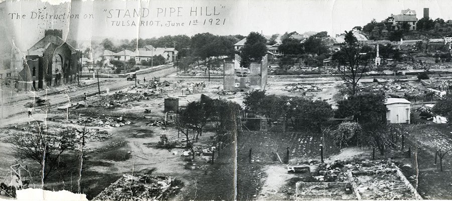 A photograph from a hilltop shows the utter destruction of several city blocks.