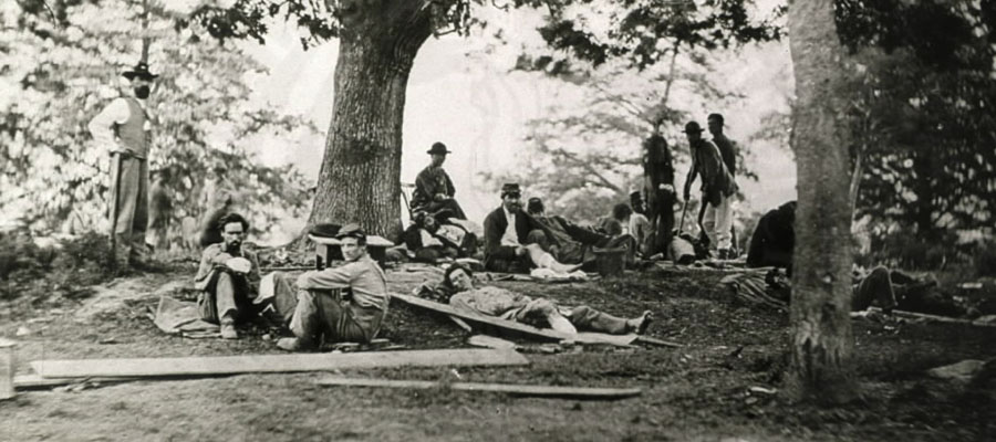 A photograph of wounded soldiers camped under a tree.