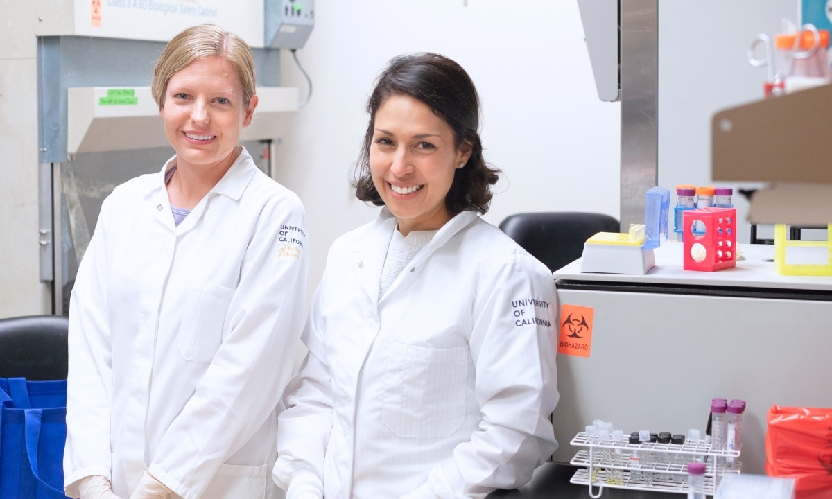 Two researchers in biomedical lab wearing University of California lab coats.