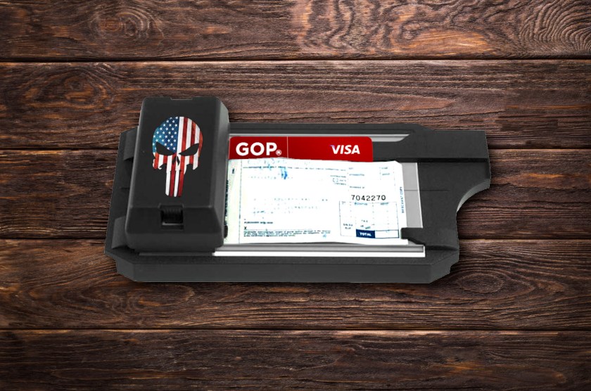 A mechanical credit card imprinter (AKA 'zipzap') emblazoned with a US flag Punisher logo. It is imprinting a blank credit-card slip with a red Visa card bearing the GOP logo. It sits on a weathered wooden plank table, stained a dark brown.